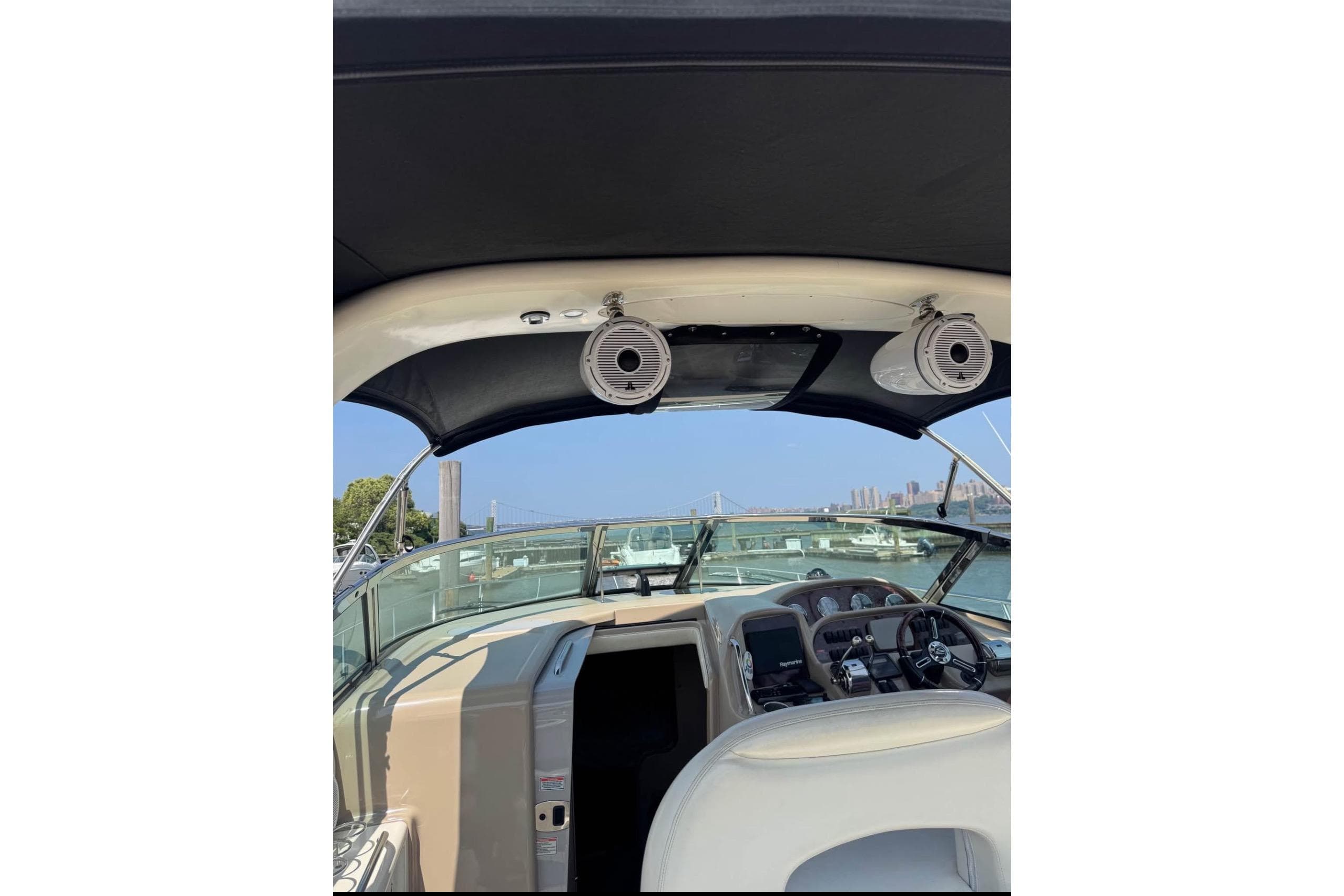 2003 Sea Ray 360 Sundancer cockpit with speakers, steering wheel, and marina view.