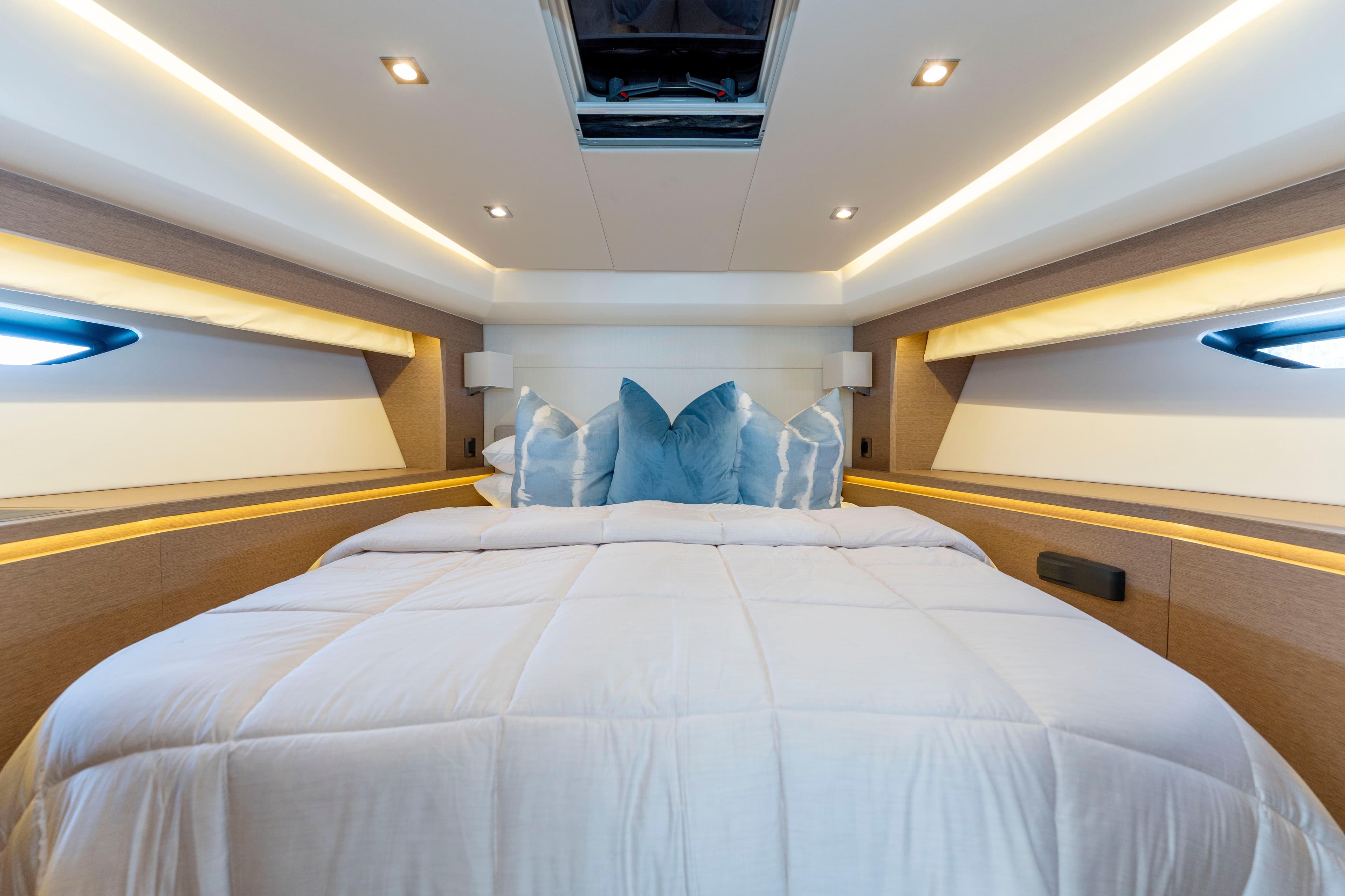 Luxurious bedroom interior of 2018 Prestige 560 yacht with elegant bedding and ambient lighting.