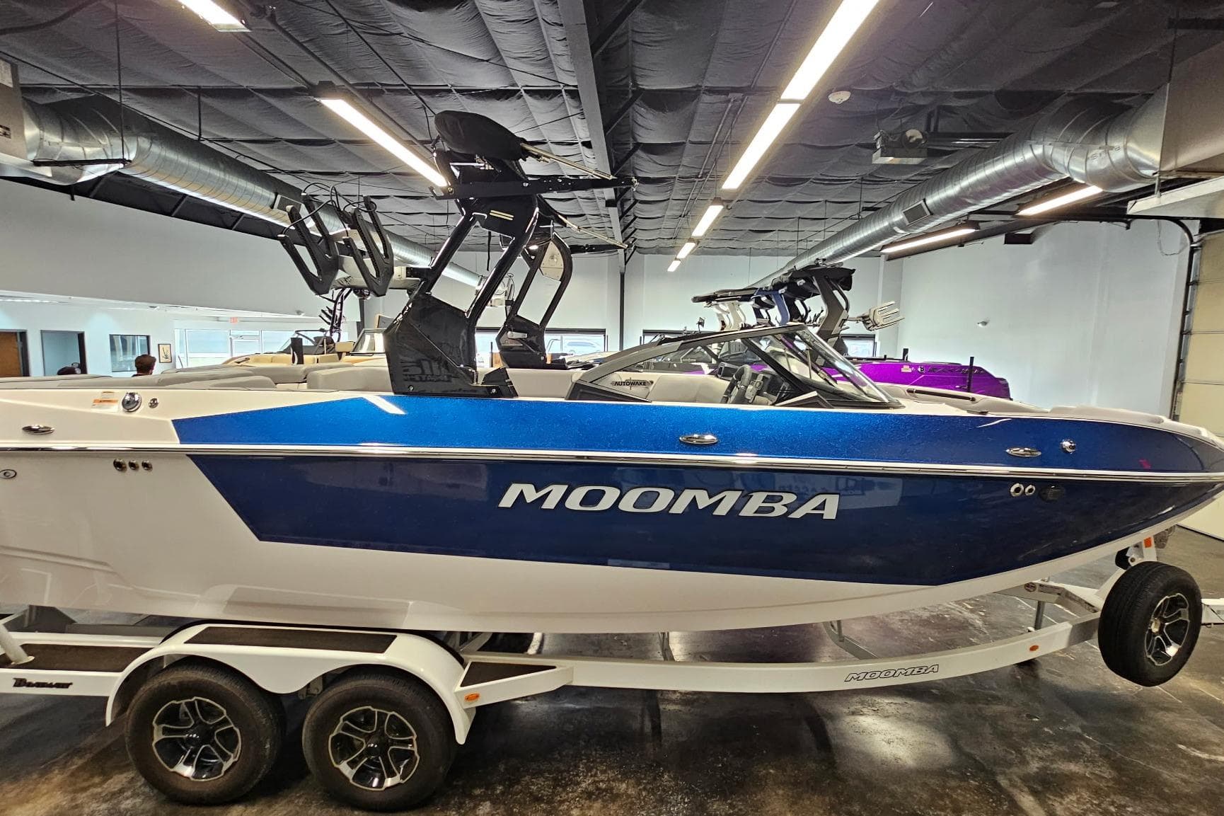 2024 Moomba Mojo boat in showroom, blue and white design, on a trailer.