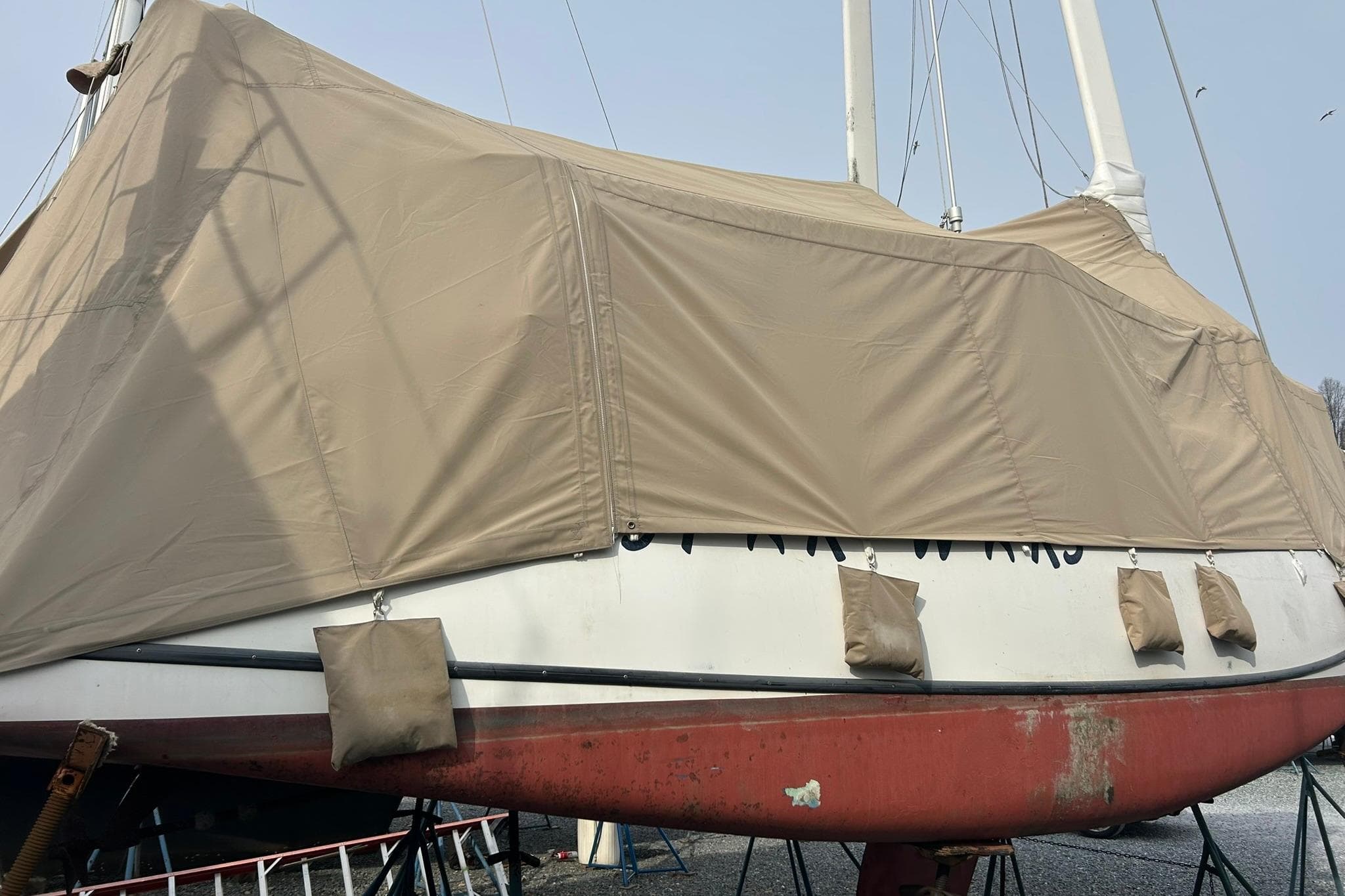 1991 Tillotson-Pearson Manta sailboat covered with beige tarp on dry dock.