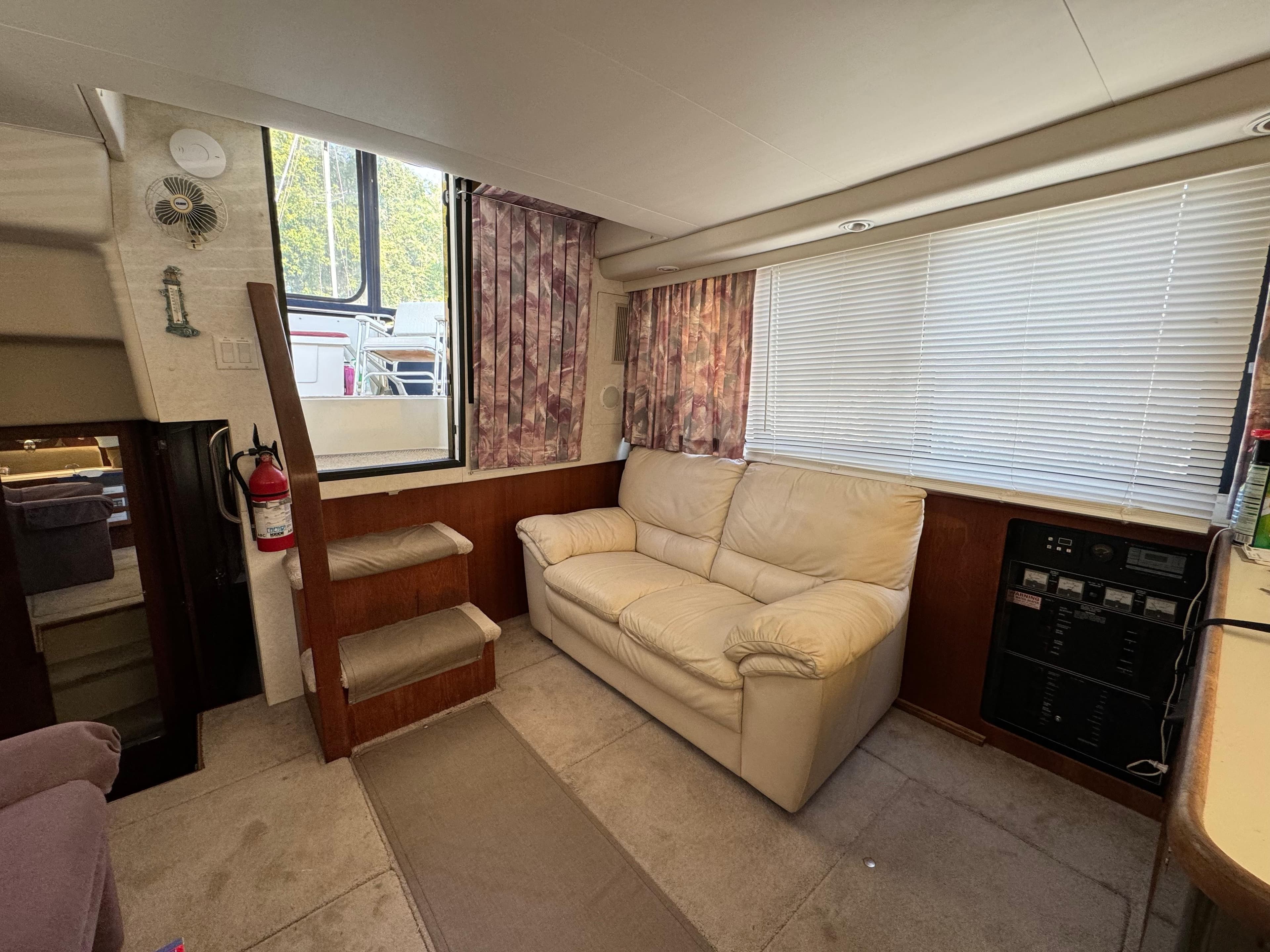 Interior of 1991 Carver 33 Aft Cabin with sofa, stairs, and window blinds.