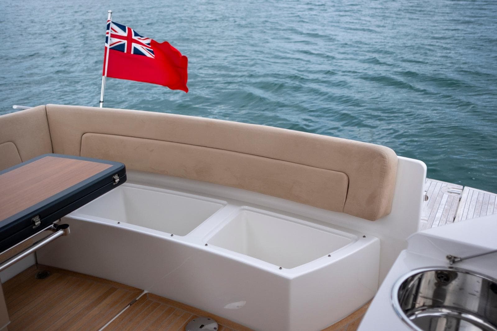 Luxury seating area on 2019 Windy 46 Chinook yacht with flag, overlooking water.