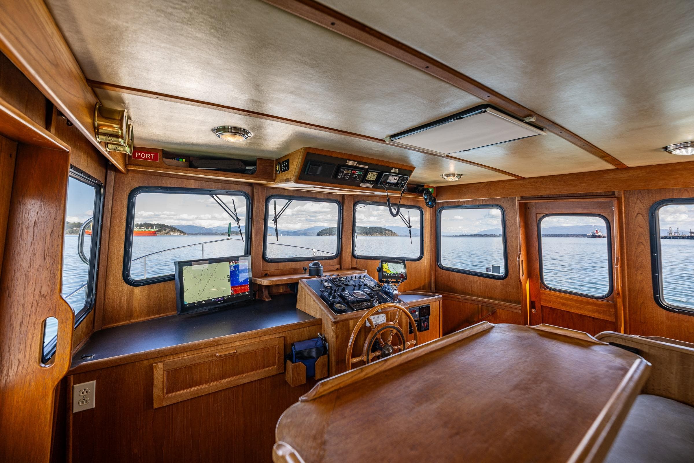 Pilothouse interior of a 1997 Nordic Tug 42, featuring navigation equipment and panoramic windows.
