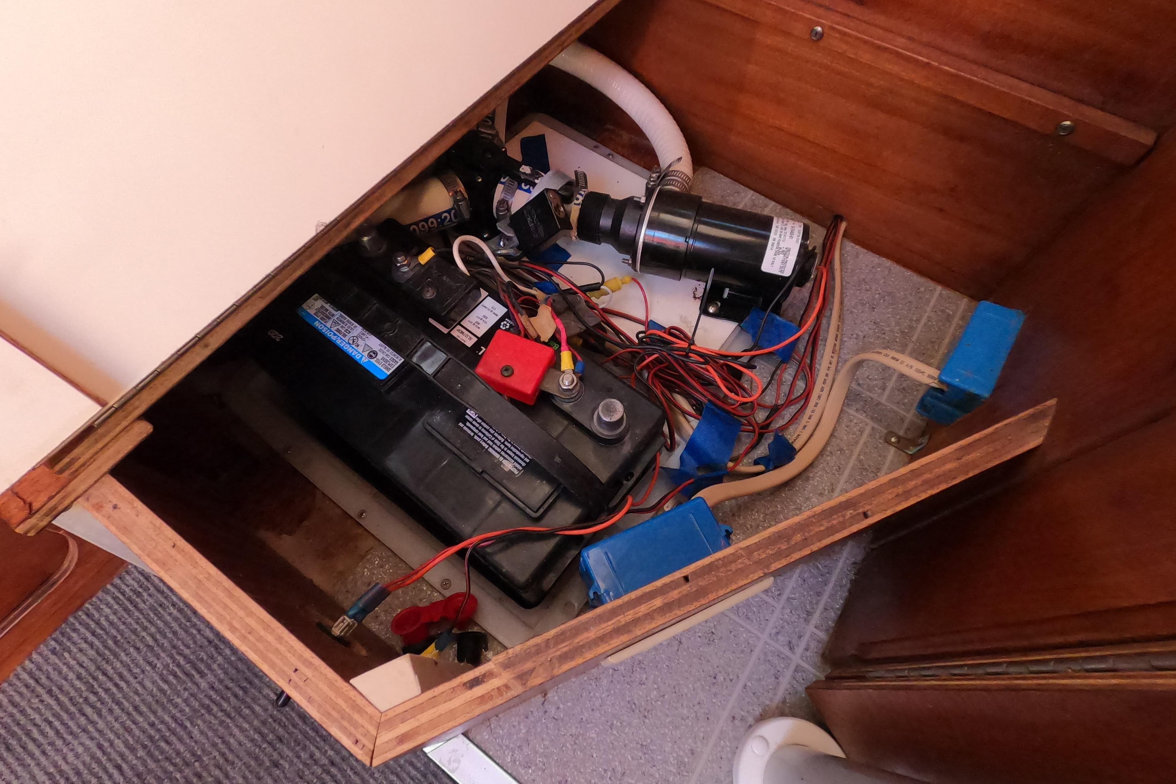 Electrical compartment of a 1996 Rhodes 22 boat with battery and wiring.