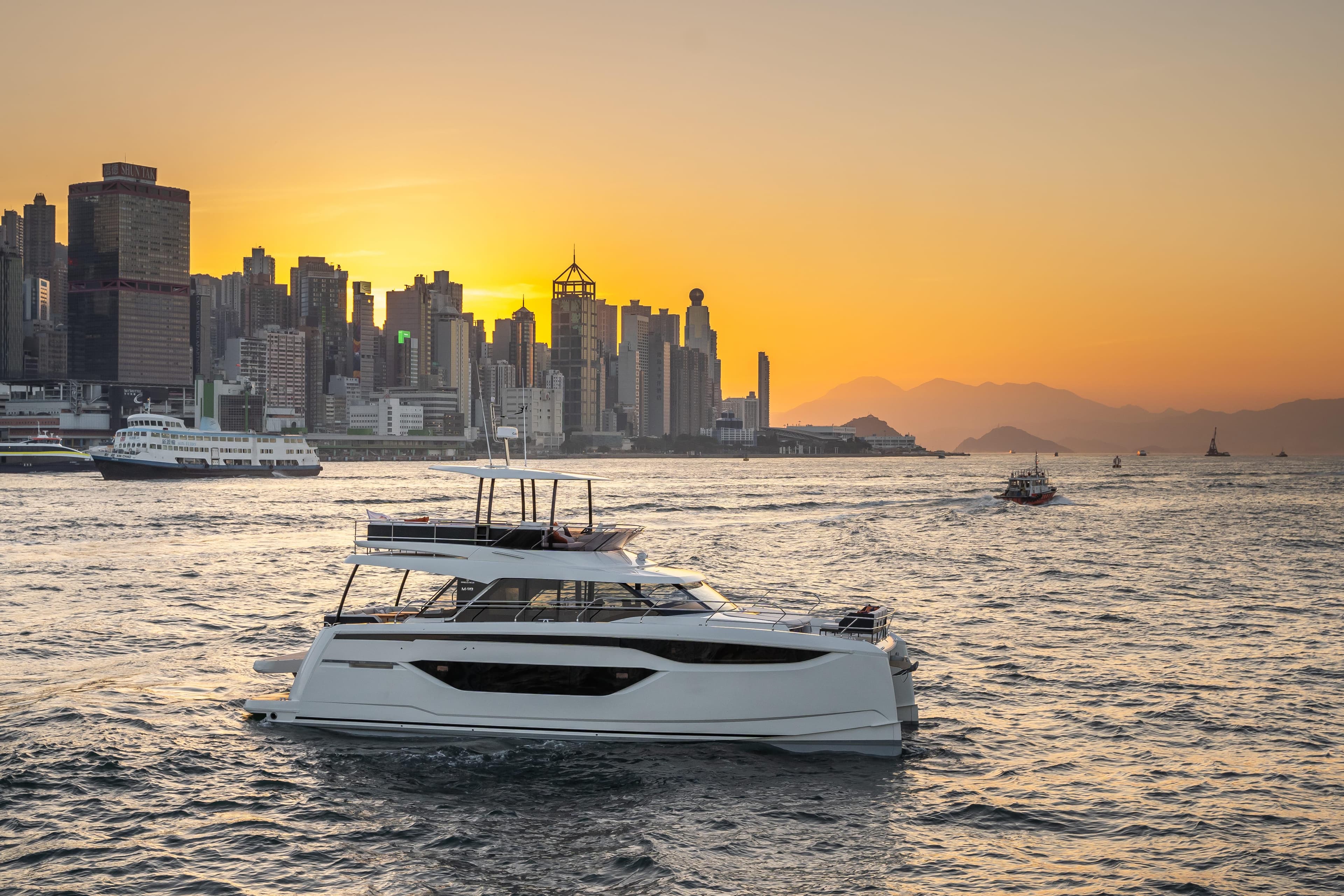 Luxury Prestige M48 yacht cruising at sunset near city skyline, 2025 model.
