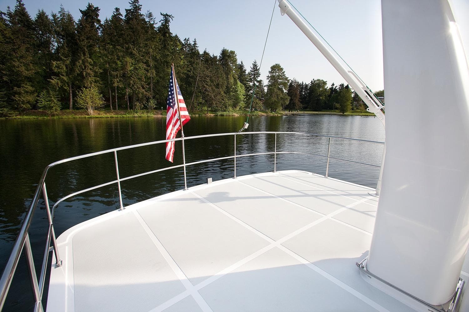 Helmsman Trawlers 43 Pilothouse 2026 yacht deck with American flag, serene lake view.