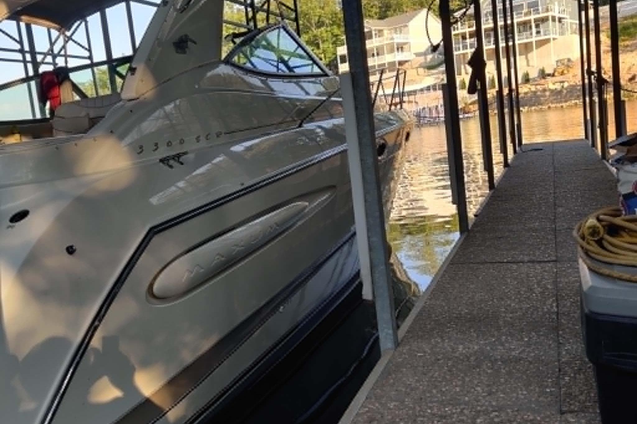 2001 Maxum 3300 SCR boat docked in a marina, reflecting on calm water.