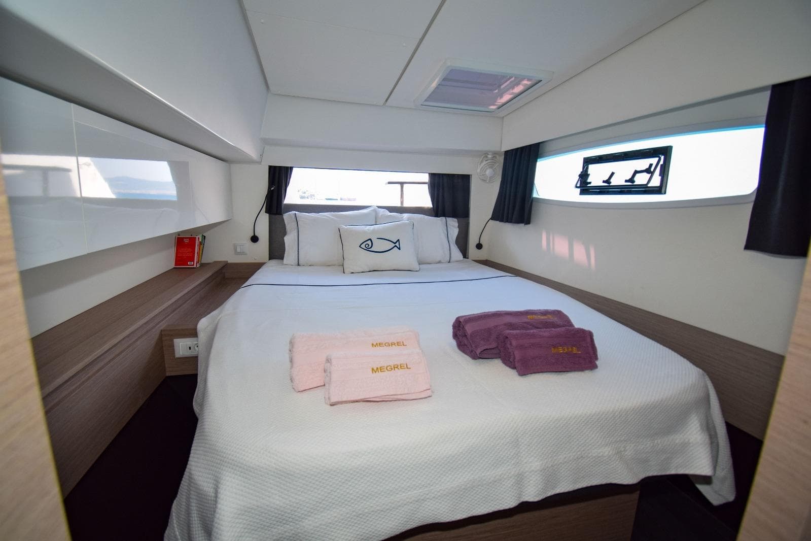 Luxurious cabin interior of 2020 Fountaine Pajot Elba 45 catamaran with cozy bed and towels.