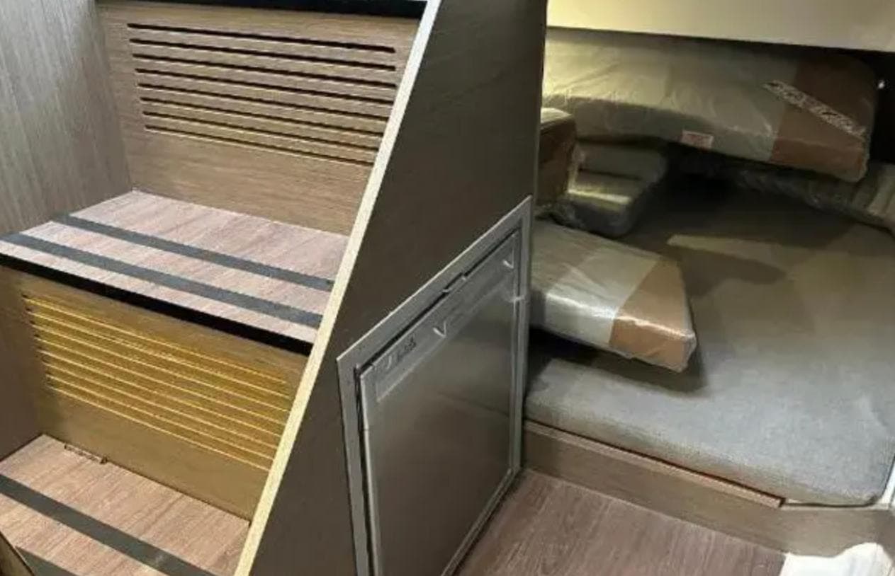 2023 Beneteau Flyer 9 interior with wooden stairs and cozy sleeping area.