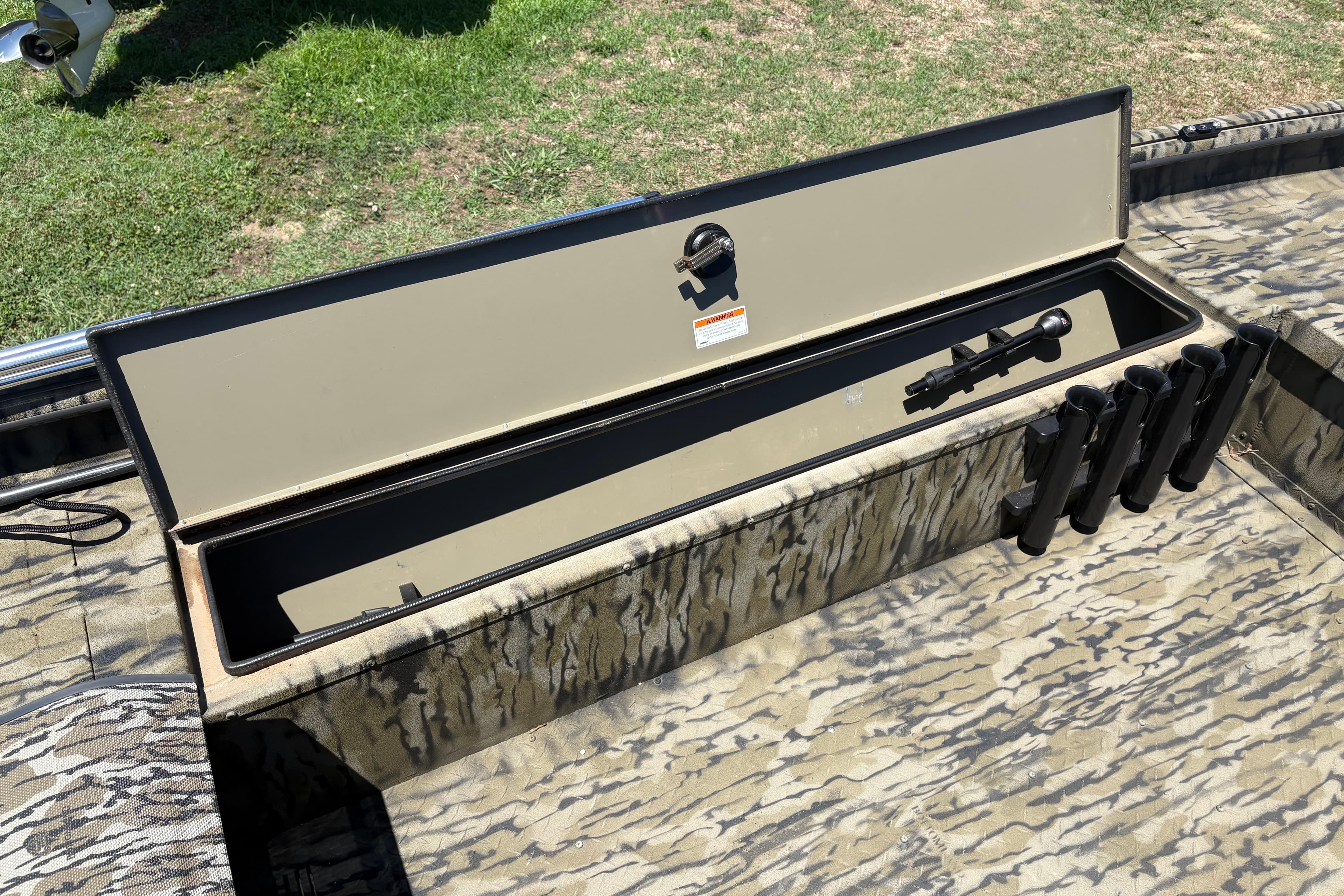 2024 SeaArk Shadow 17 boat storage compartment with camouflage design and rod holders.