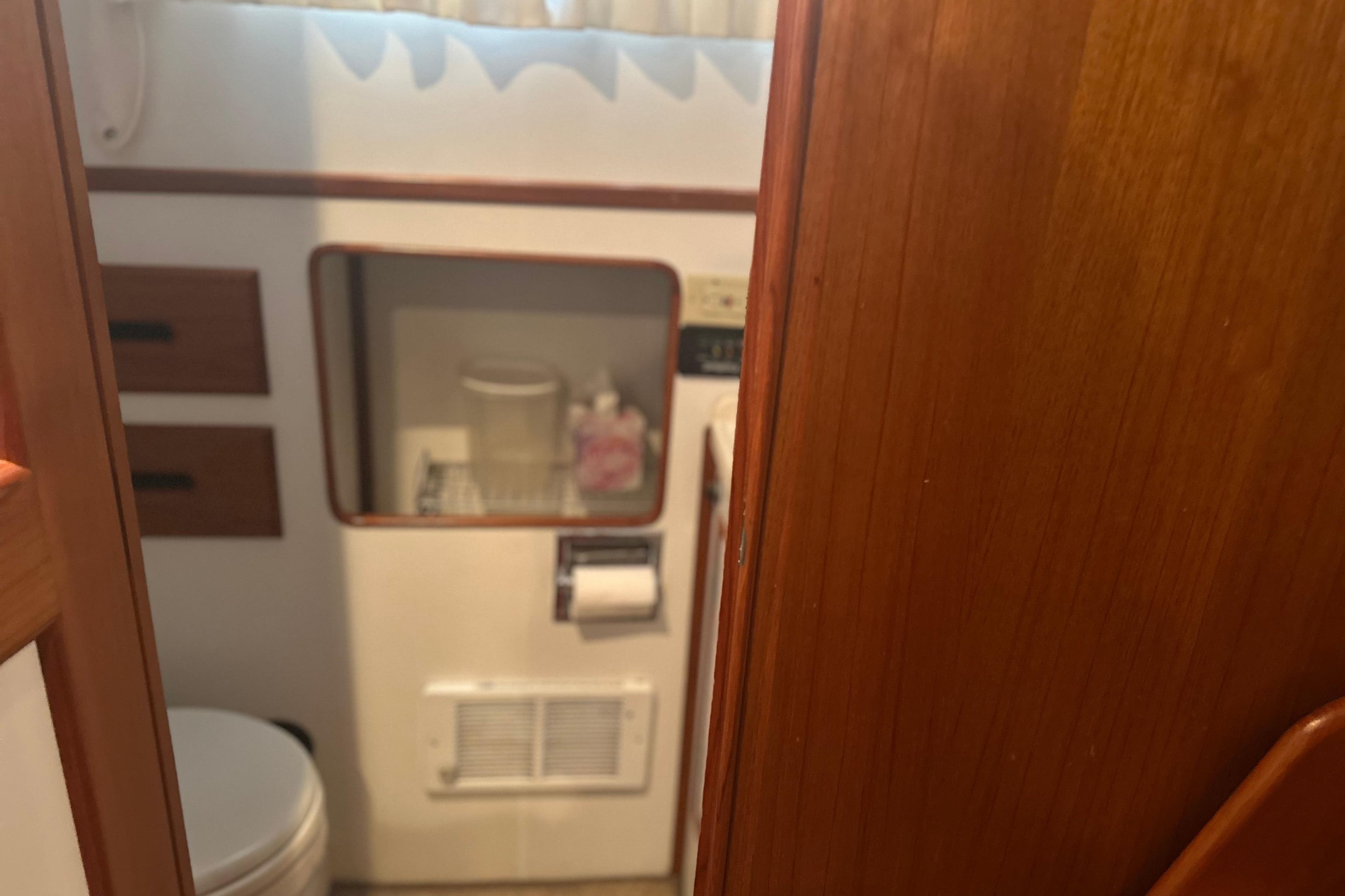Bathroom interior of a 2000 Island Gypsy 36 boat with wooden accents.