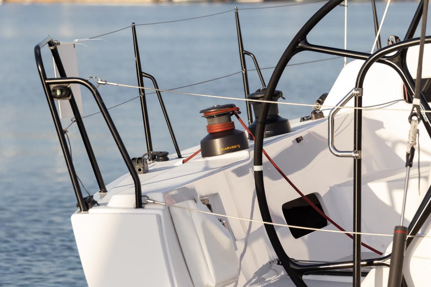 2008 J Boats J/122 sailboat deck with winch and steering wheel, docked on calm water.