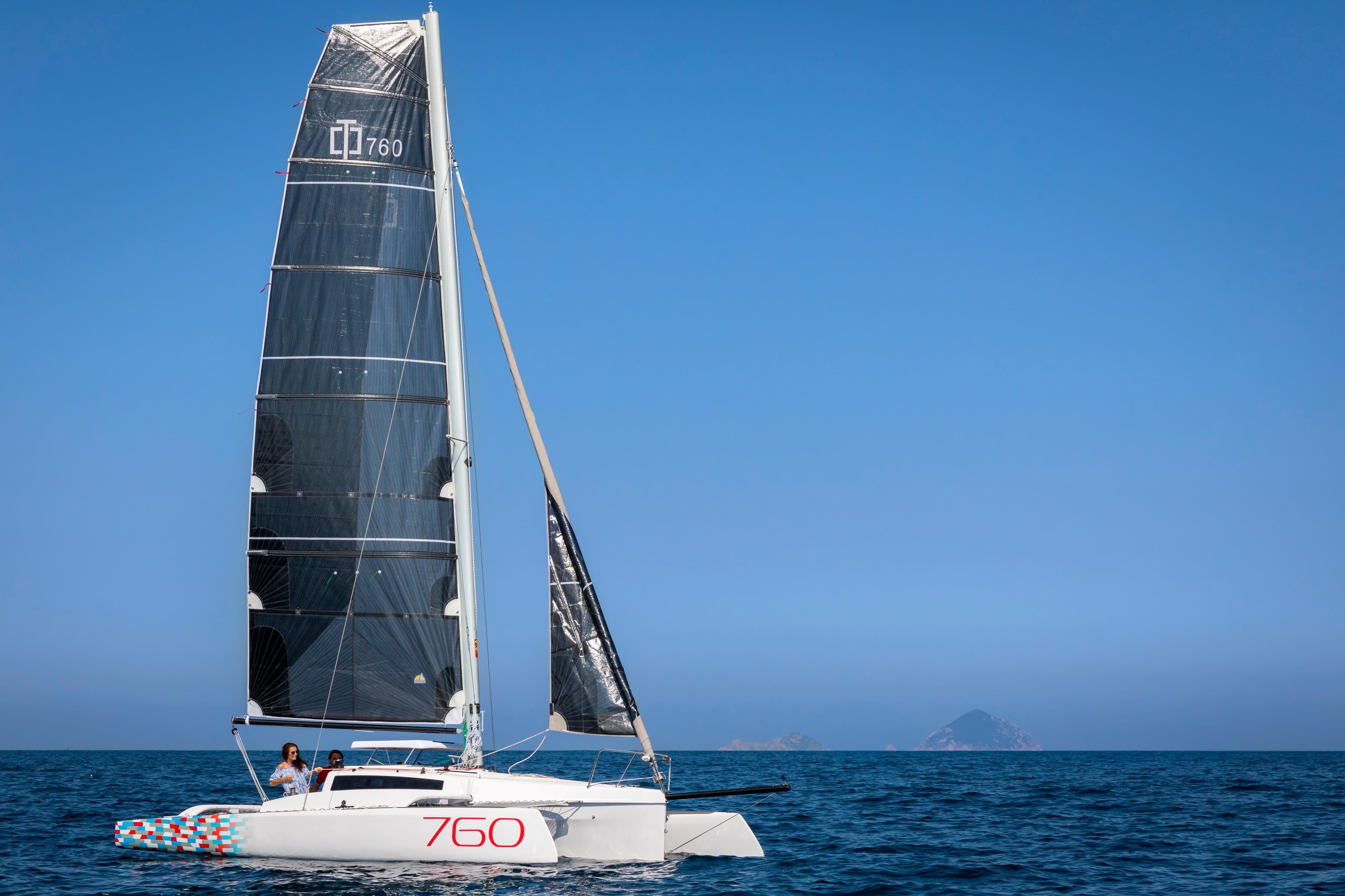 Sleek 2026 Corsair 760 sailboat gliding on open sea under clear blue sky.