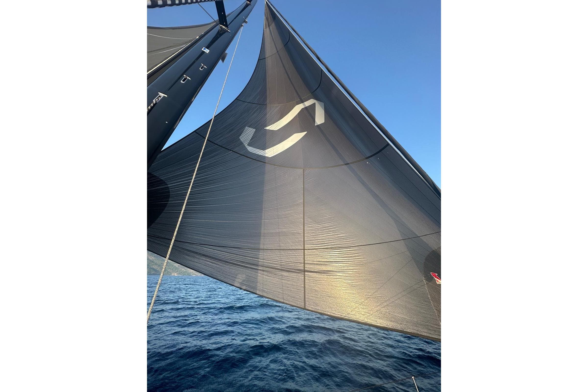 Sailing yacht Solaris 55, 2023 model, with black sail against clear blue sky.