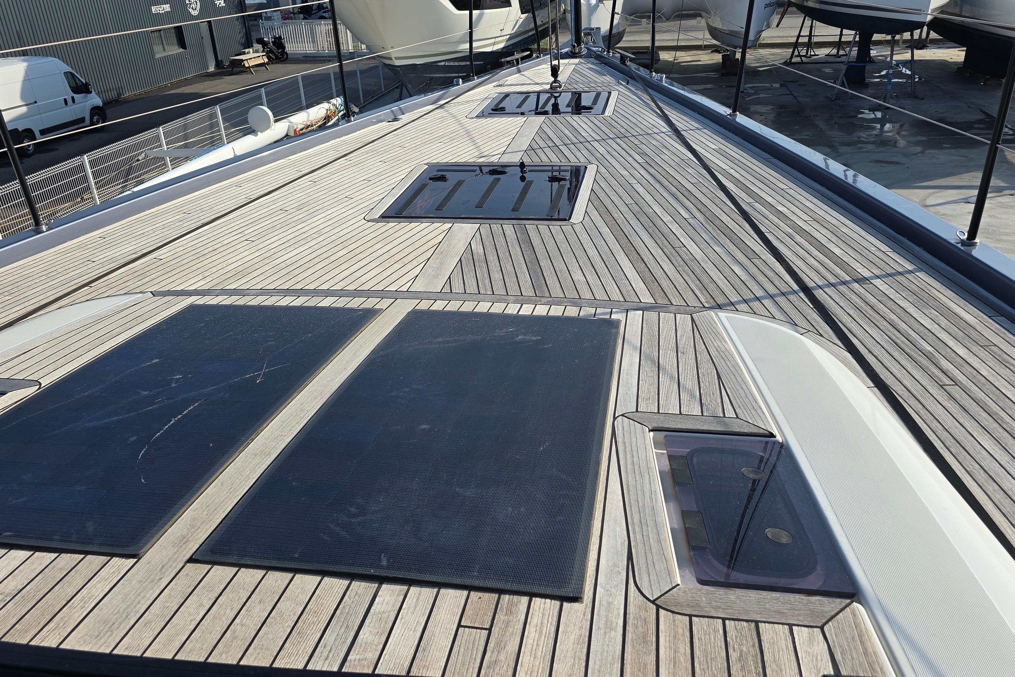 Deck of 2022 Beneteau First 53 yacht with sleek wooden finish and hatches.