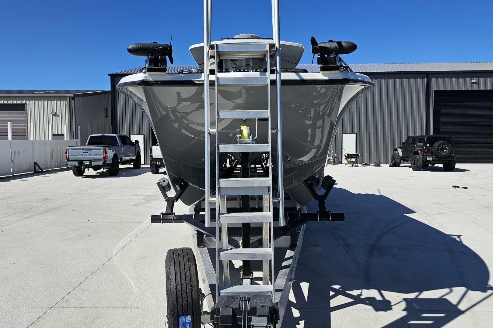 2025 Costa Custom Boats 34ST on trailer, parked in industrial area under clear blue sky.