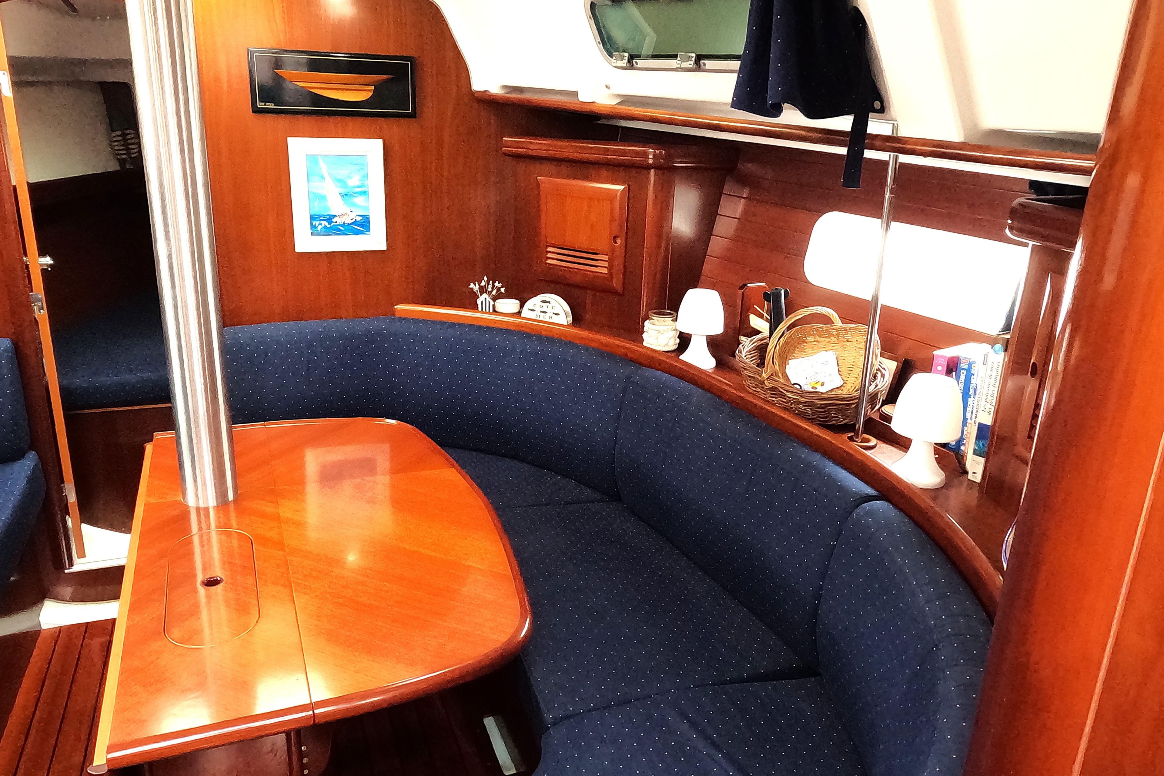 Interior of 2003 Beneteau Oceanis Clipper 361 with wooden table and blue seating.
