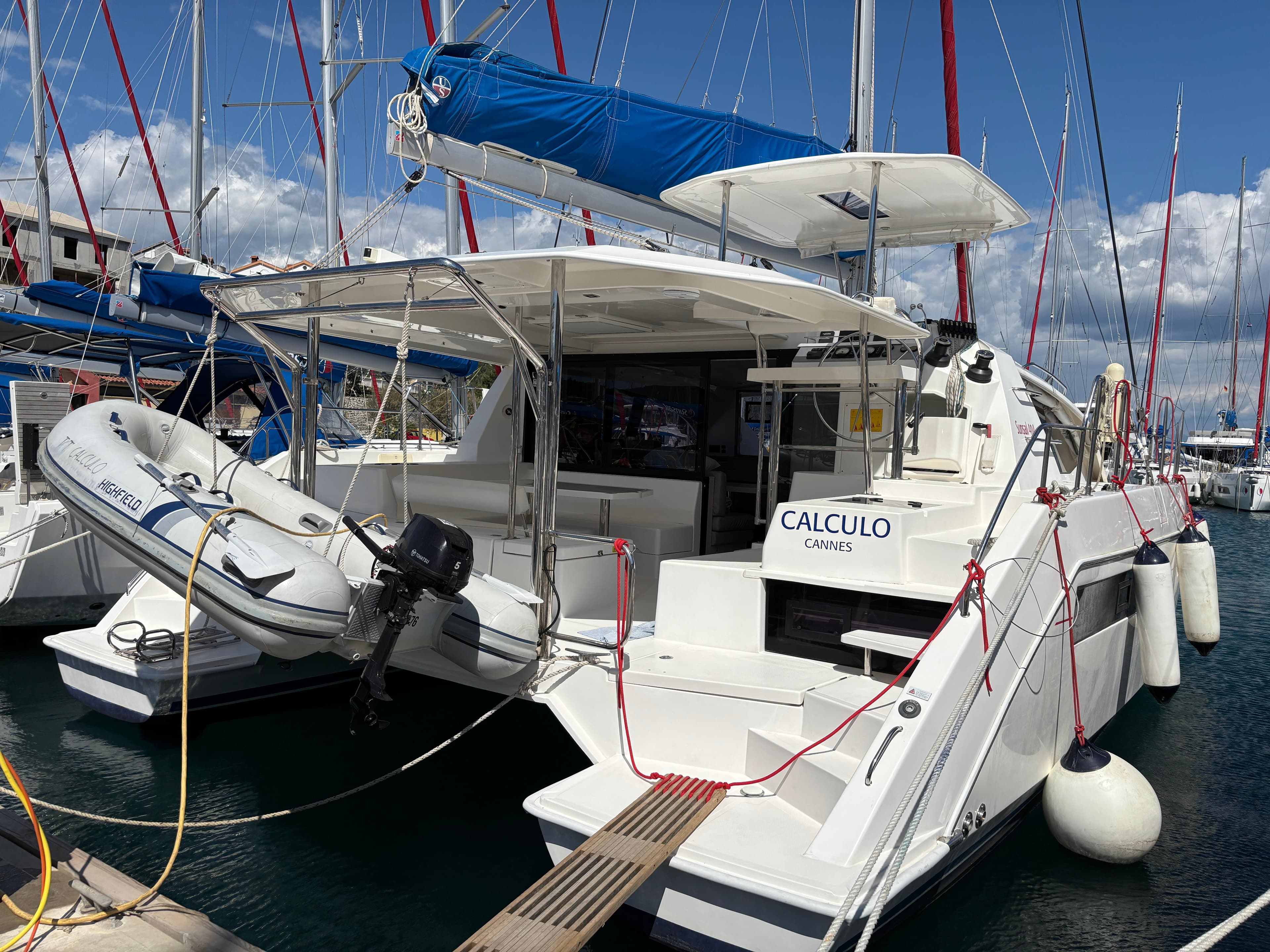 2019 Leopard 40 catamaran docked with dinghy, blue sail cover, and marina backdrop.