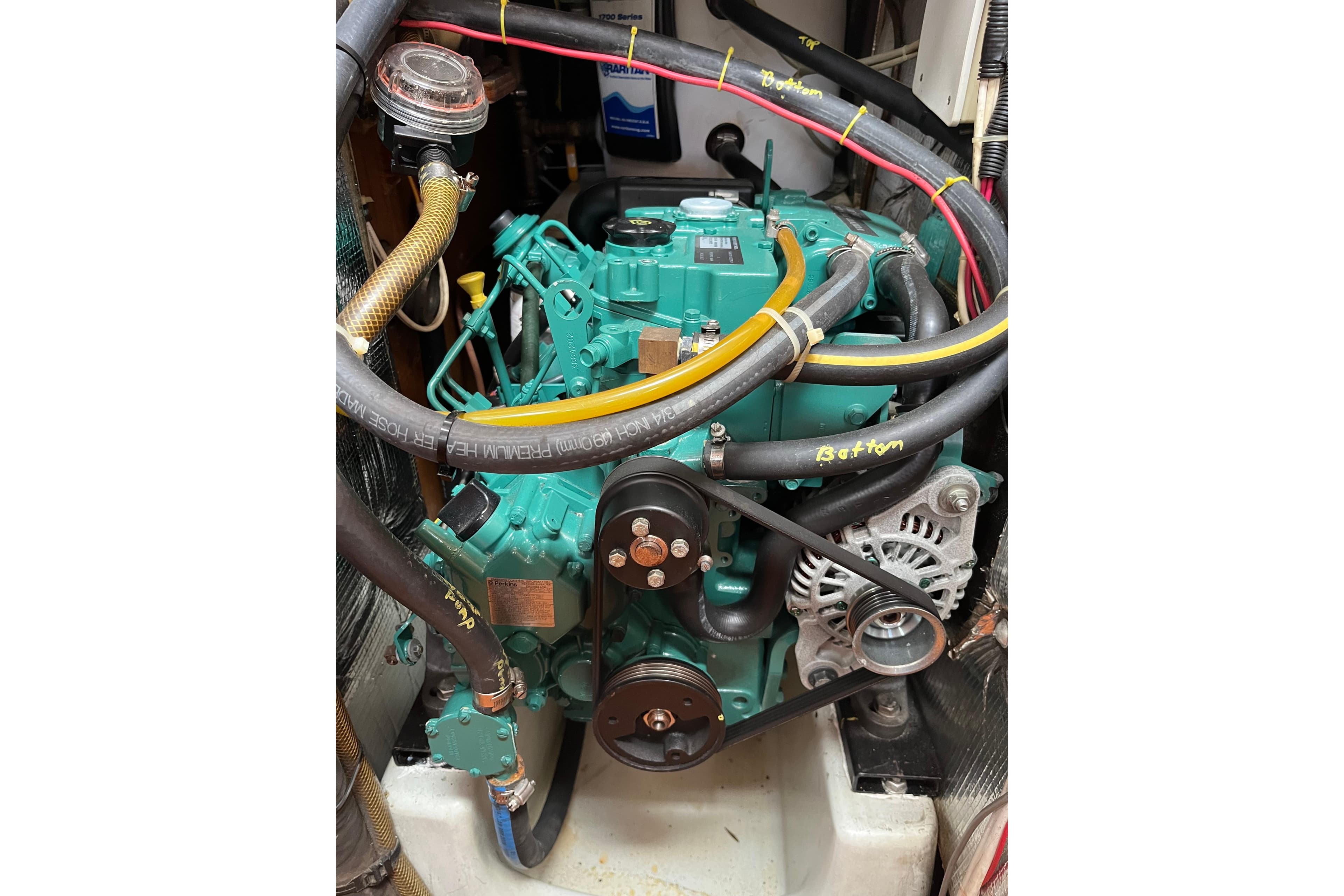 Engine compartment of a 1986 Wauquiez Petorine sailboat, featuring hoses and mechanical components.