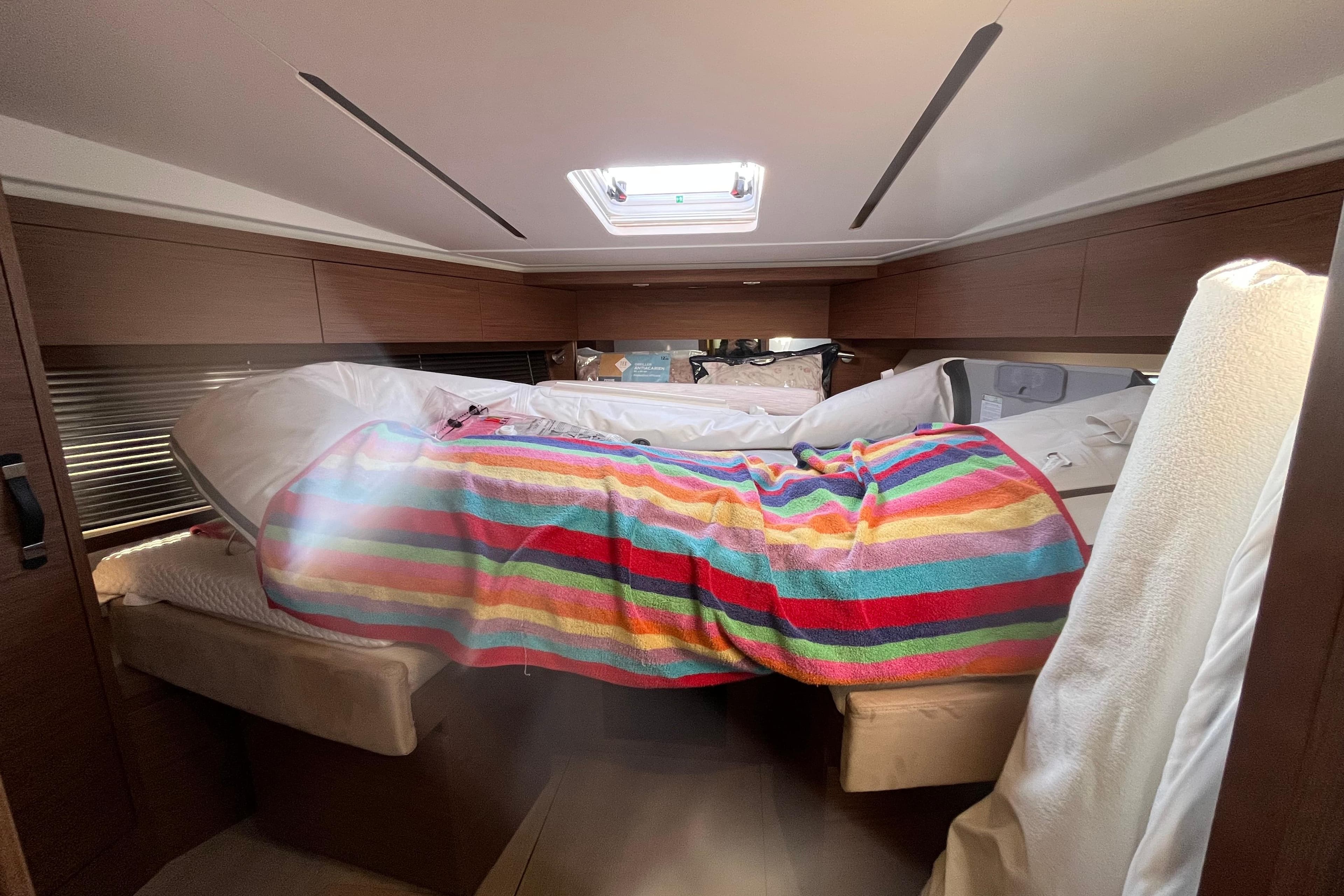 Interior cabin of 2016 Jeanneau Leader 46 yacht with colorful striped blanket.