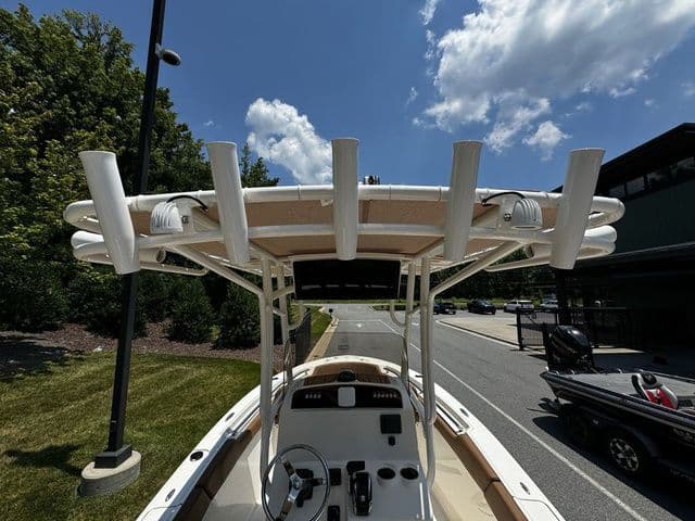 2025 Pioneer ISLANDER 202 boat with T-top and rod holders, parked outdoors under a blue sky.