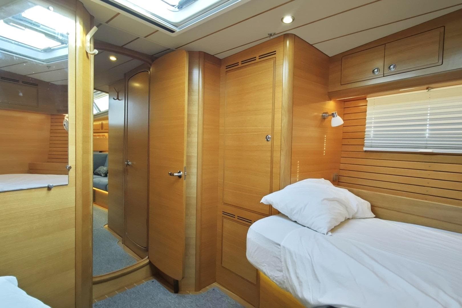 Luxurious interior of 2020 Hallberg-Rassy 57 yacht with wooden finish and cozy bedding.