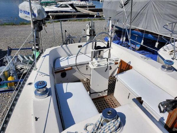 1977 Ontario Yachts 32 sailboat cockpit with steering wheel and winches, docked near water.