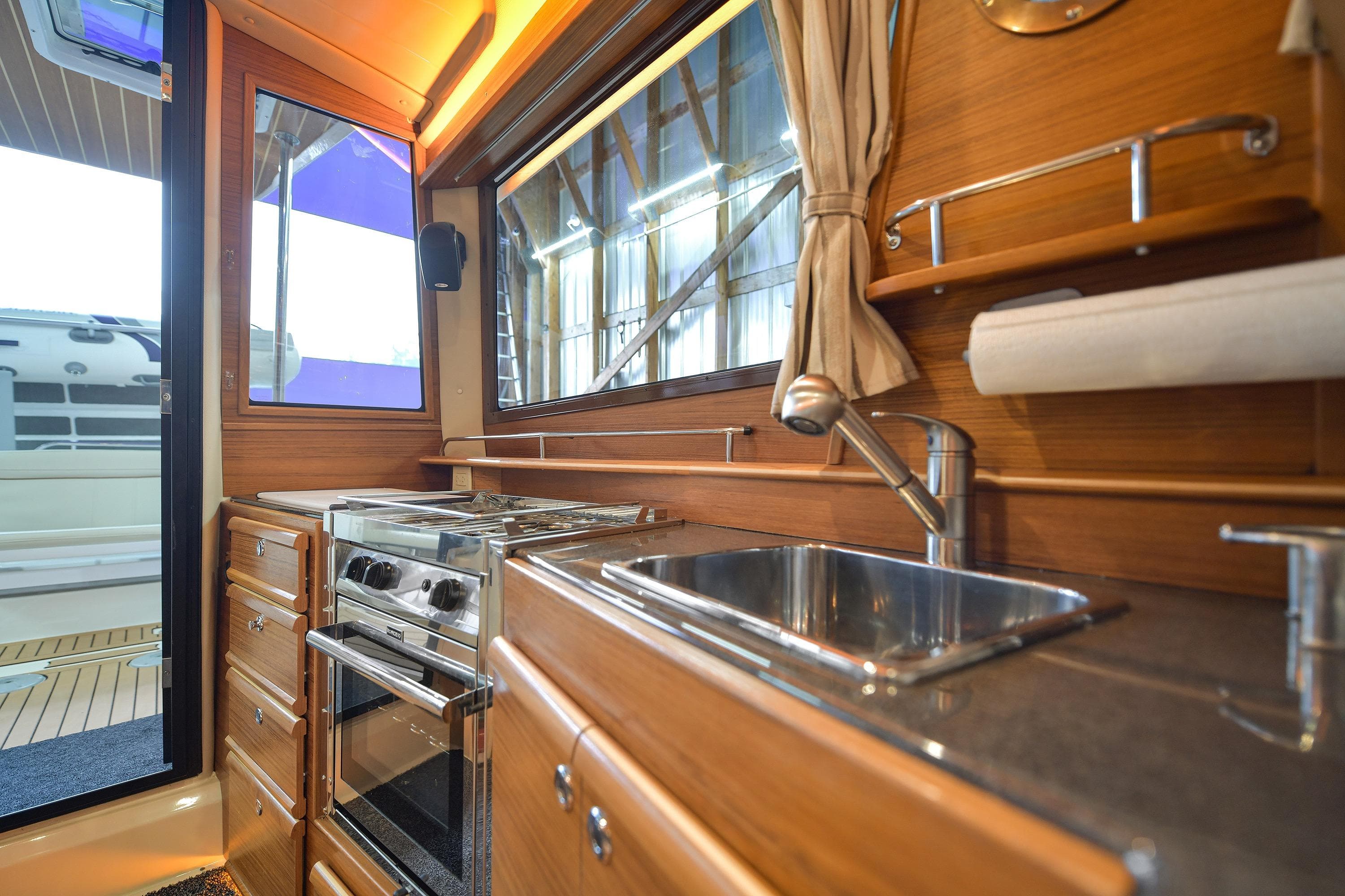 2023 Ranger Tugs R-29S interior kitchen with stove, sink, and wooden cabinetry.