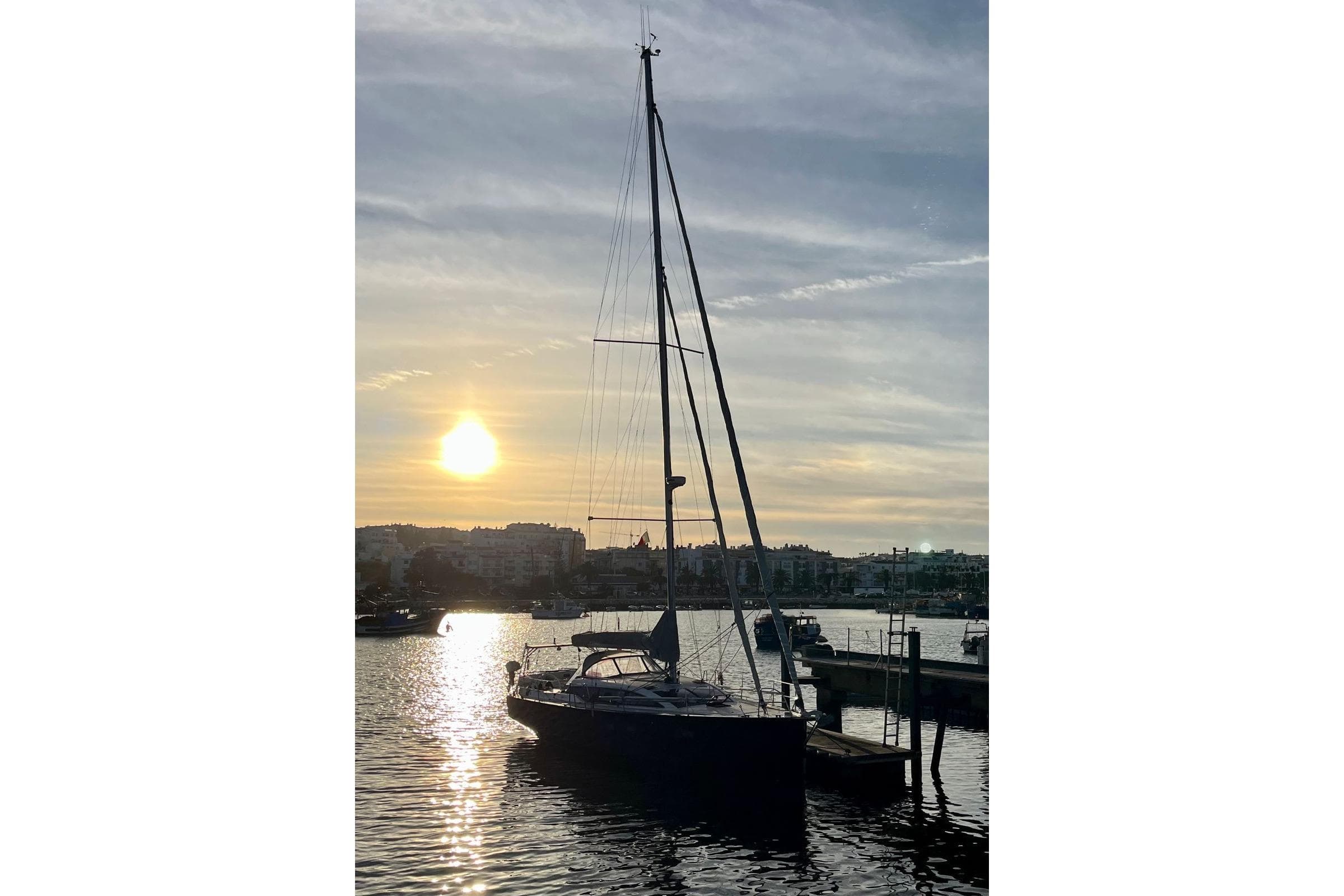 Sailboat RM Yachts 1260, 2013 model, docked at sunset in a serene harbor.