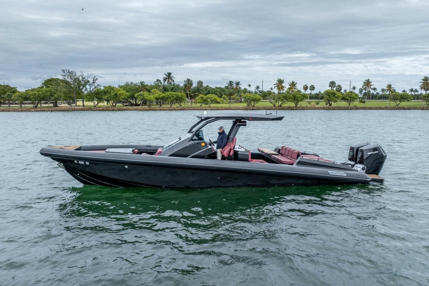 2023 Skipper-BSK 42 boat on water, sleek design, overcast sky, lush shoreline.