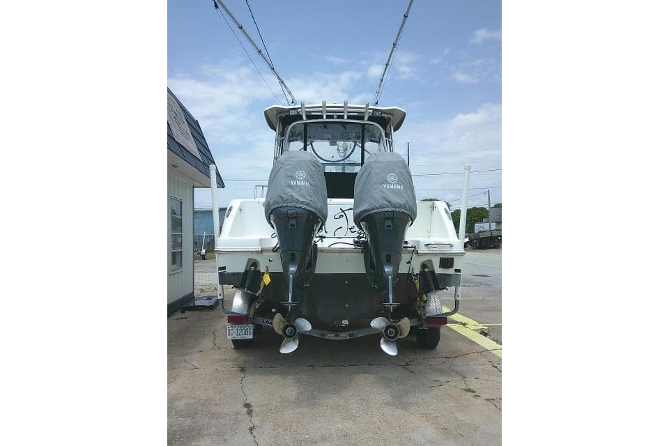 2008 Robalo R245 Walkaround boat with twin Yamaha outboard motors, docked on pavement.