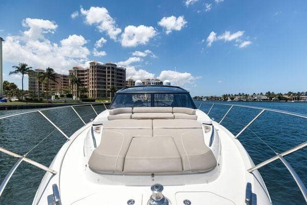 2020 Princess V55 yacht cruising near waterfront buildings under a clear blue sky.