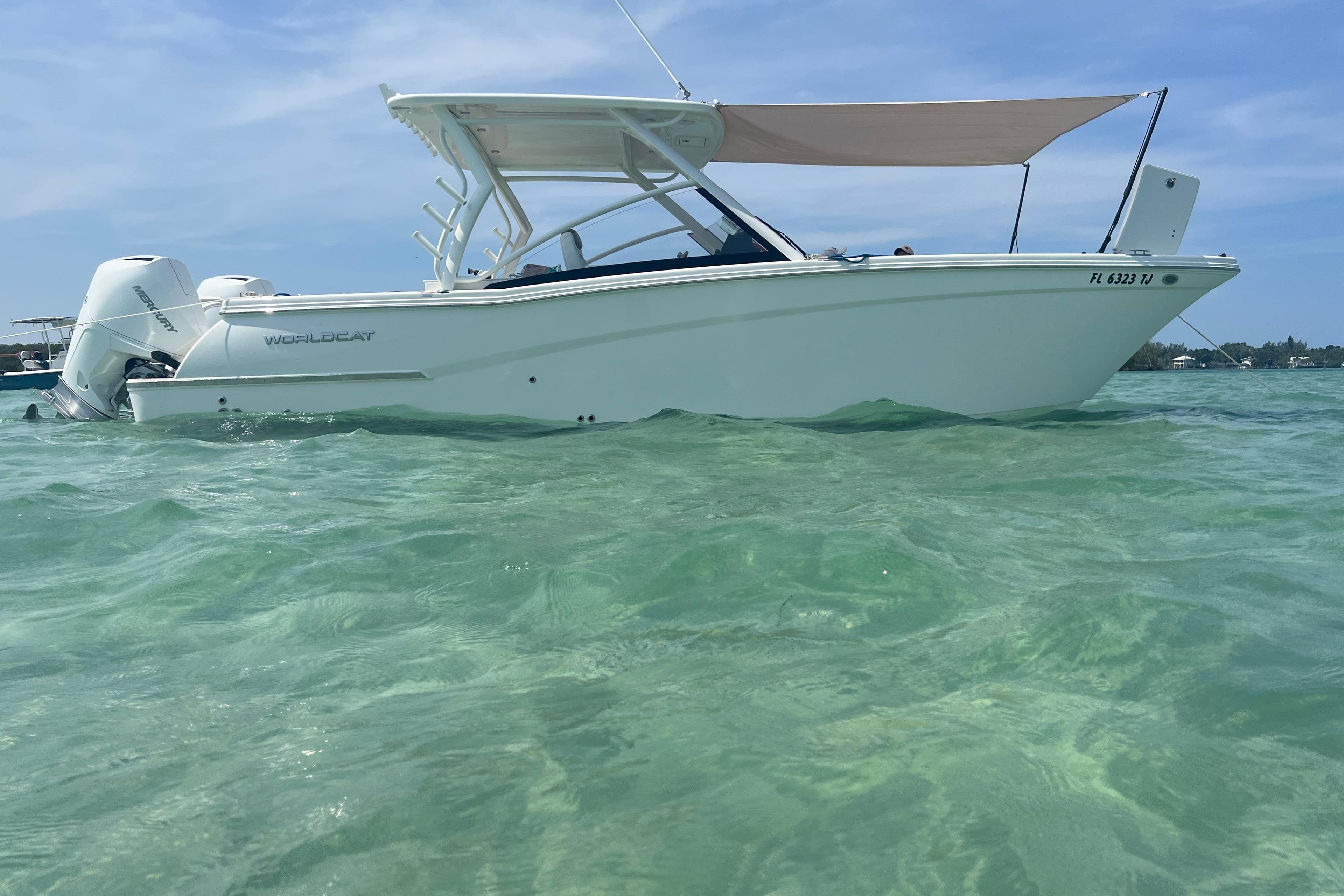 2023 World Cat 280 DC-X boat on clear turquoise water under blue sky.