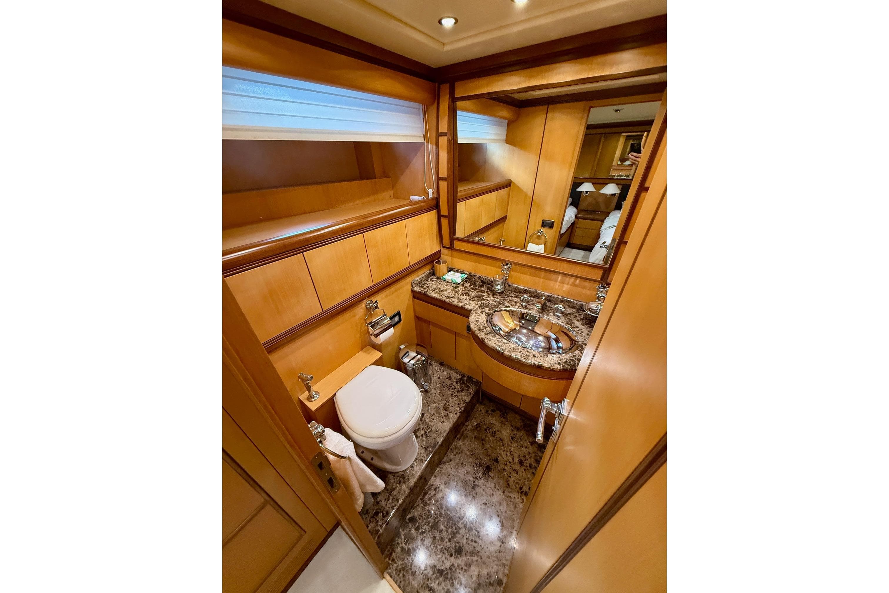 Luxurious bathroom in a 2005 Mangusta 92 yacht with marble countertop and wooden cabinetry.