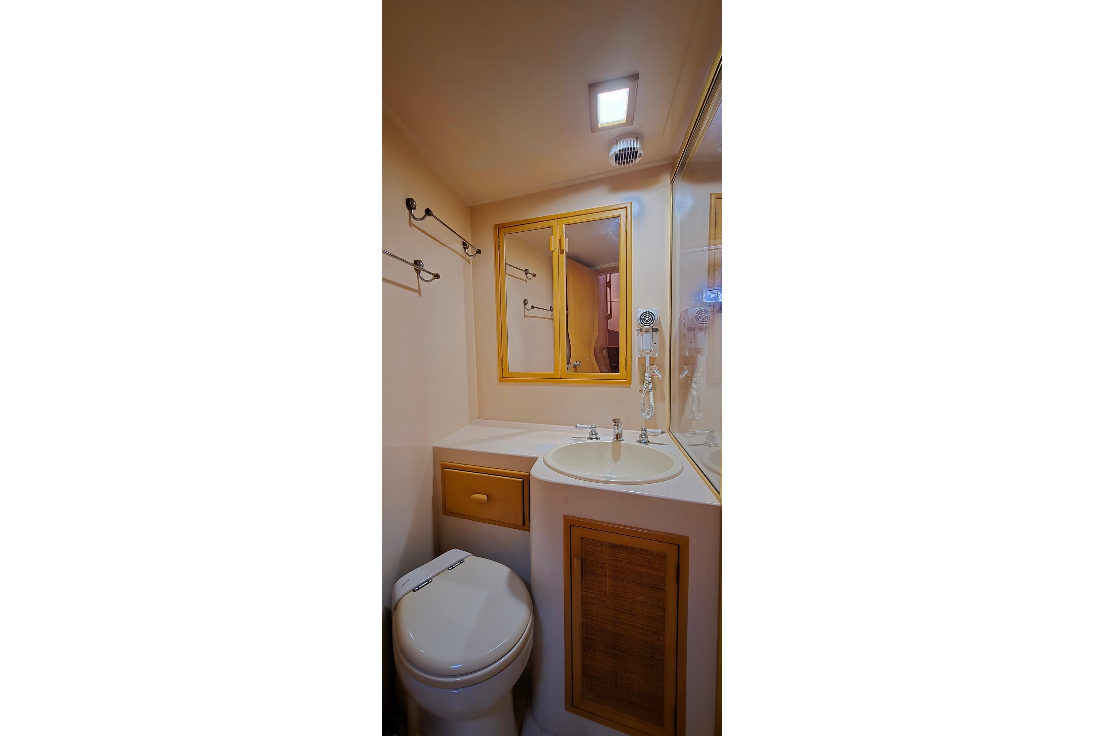 Compact bathroom in a 1987 Southern Cross 53 yacht, featuring sink, mirror, and toilet.