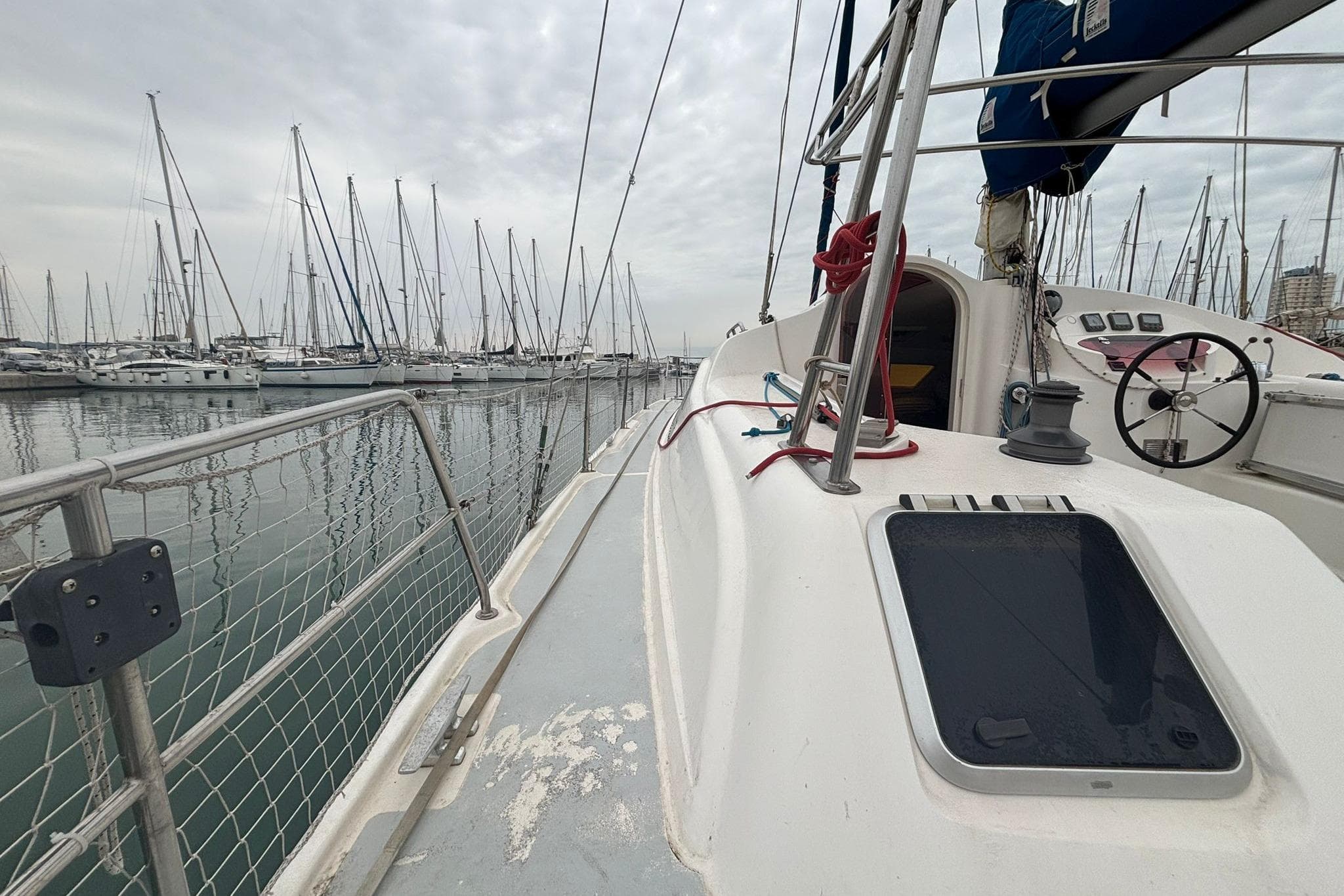 1998 Prout 38 sailboat docked in marina, surrounded by other sailboats under cloudy skies.