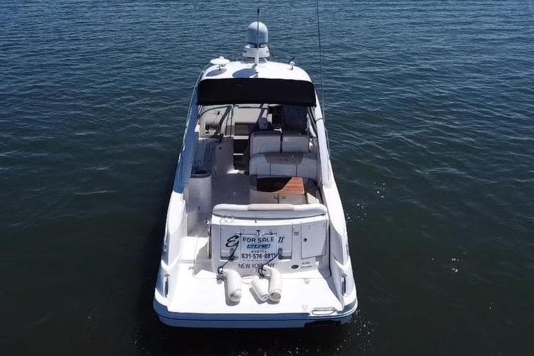 2010 Searay 330 Sundancer boat on calm water, rear view, for sale sign visible.