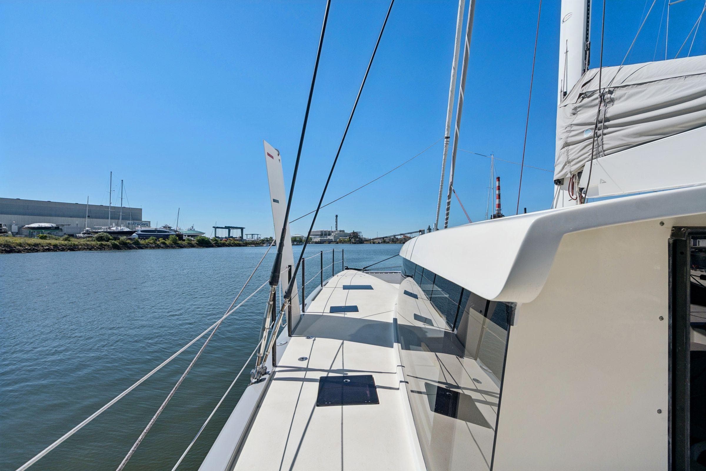 2019 Itacatamarans 14.99 sailing on a calm river under clear blue skies.