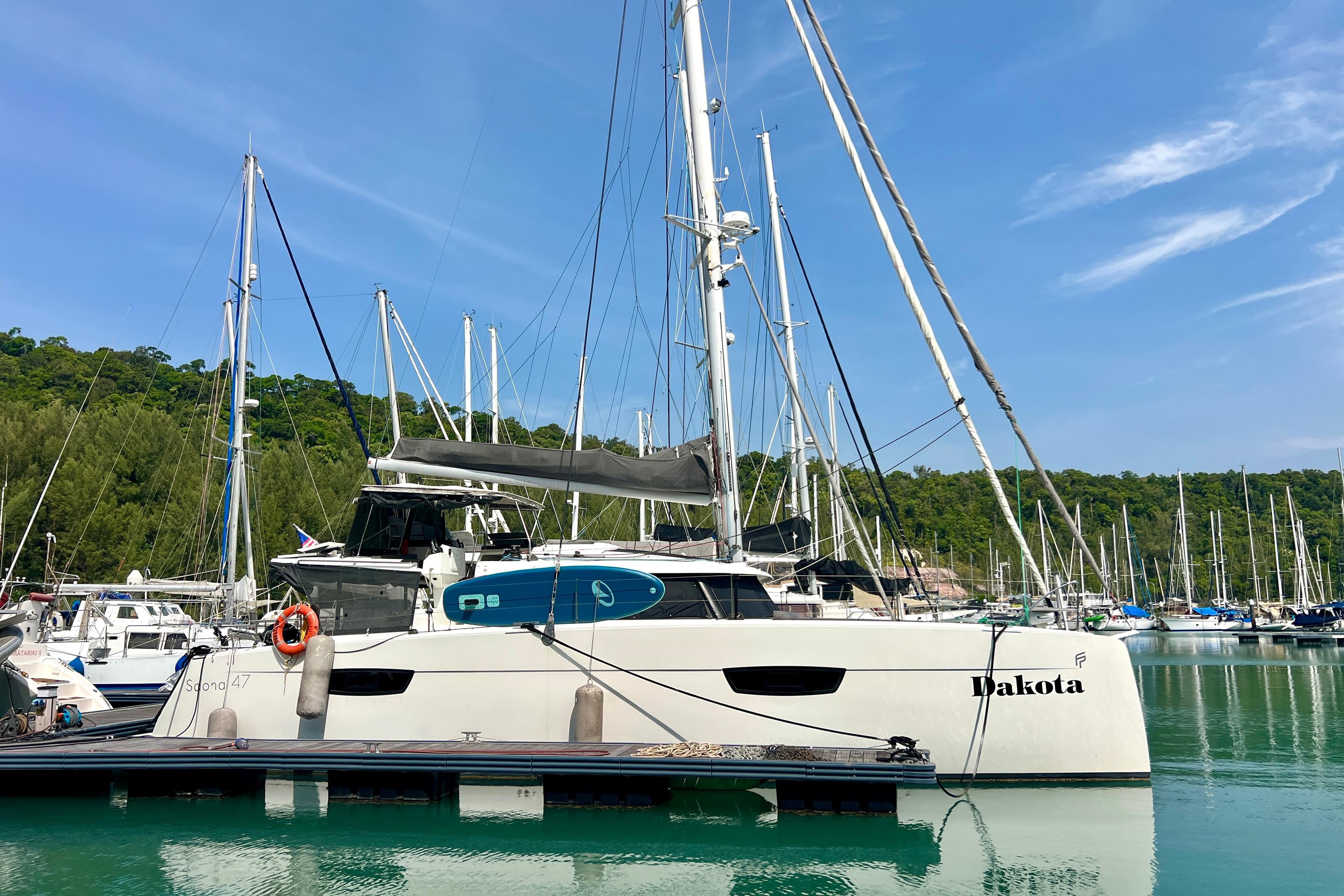 2018 Fountaine Pajot Saona 47 catamaran docked in a marina, surrounded by sailboats.