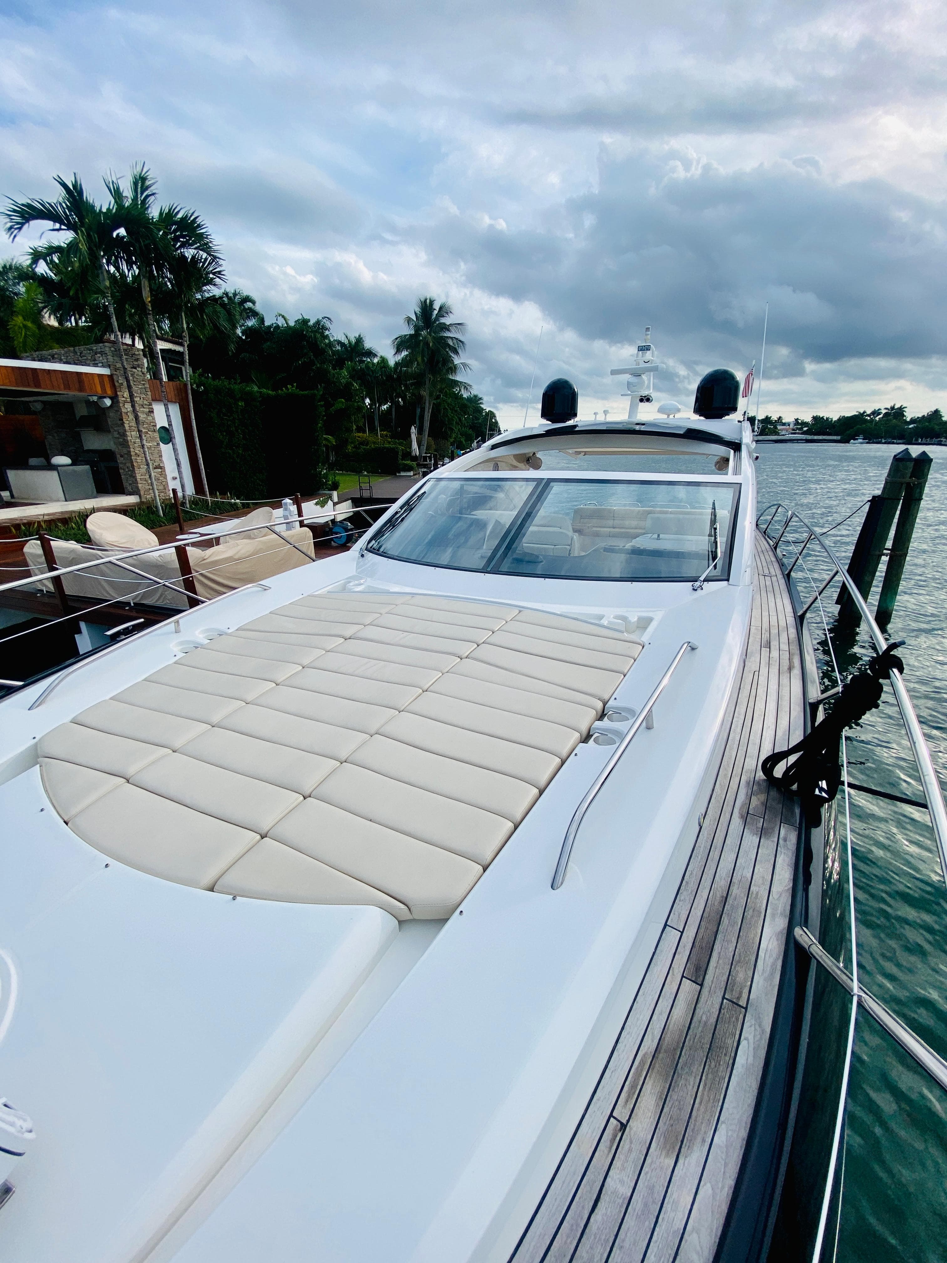 2010 Sunseeker Predator 60 luxury yacht docked by palm trees and waterfront.
