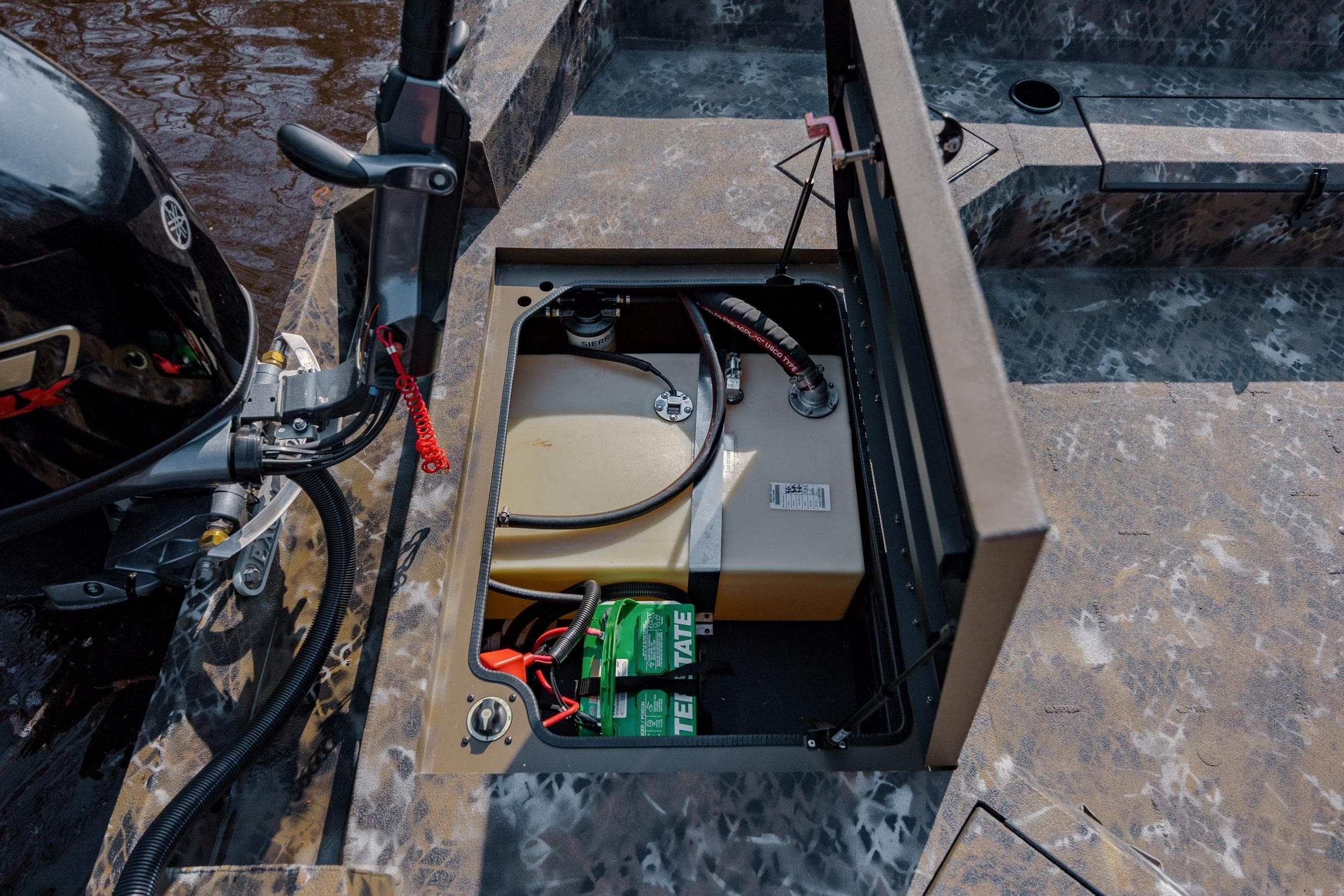 Open storage compartment in 2026 Excel 183 Tomahawk boat, showing battery and fuel tank.