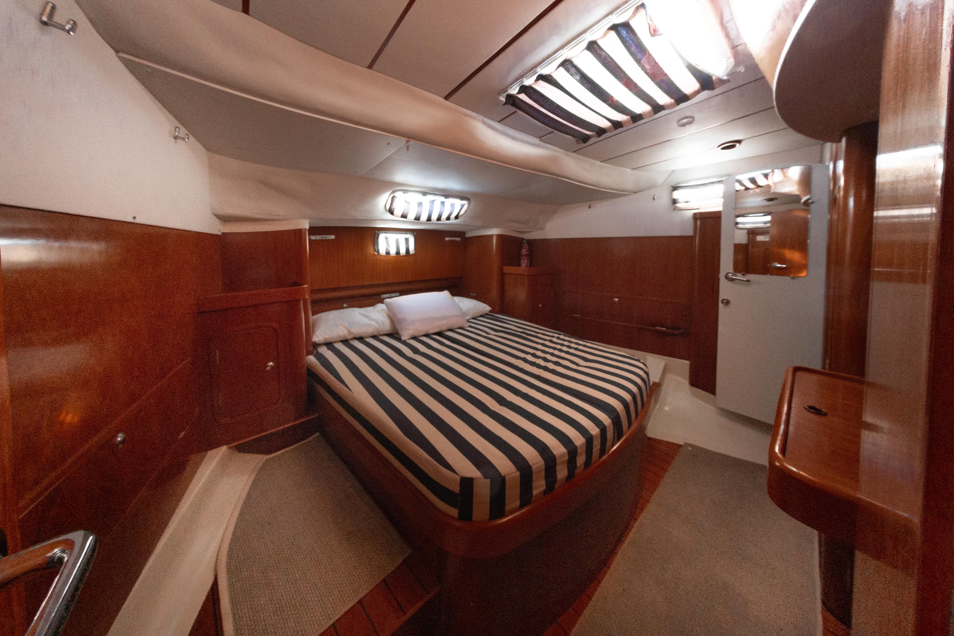 Luxurious cabin interior of 1999 Beneteau Oceanis 44 CC yacht with striped bedding.