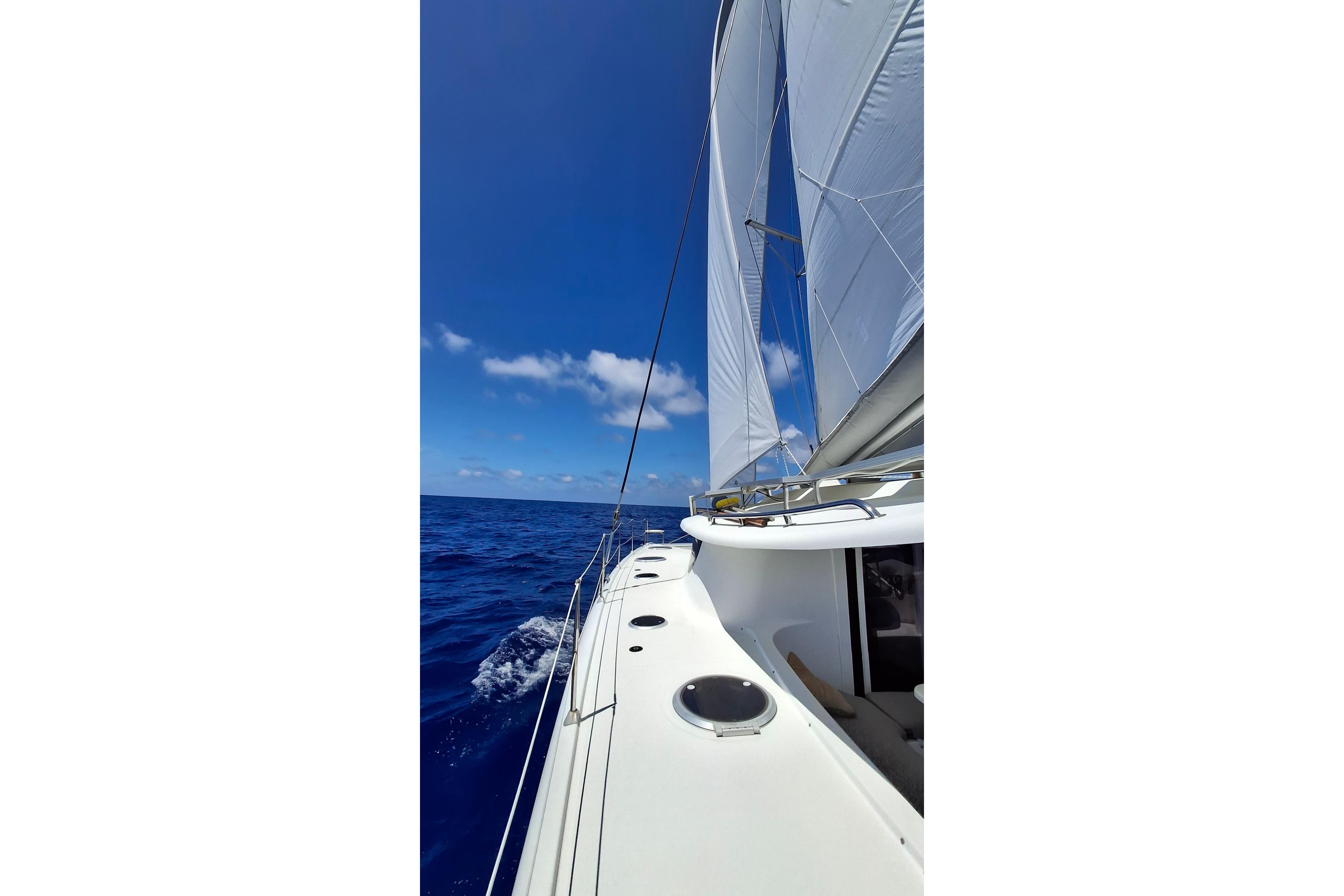 Sailing on a 2009 Fountaine Pajot Orana 44 catamaran under clear blue skies.