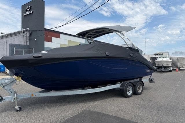 2022 Yamaha Boats 252SD on trailer, covered, parked outdoors near a building.