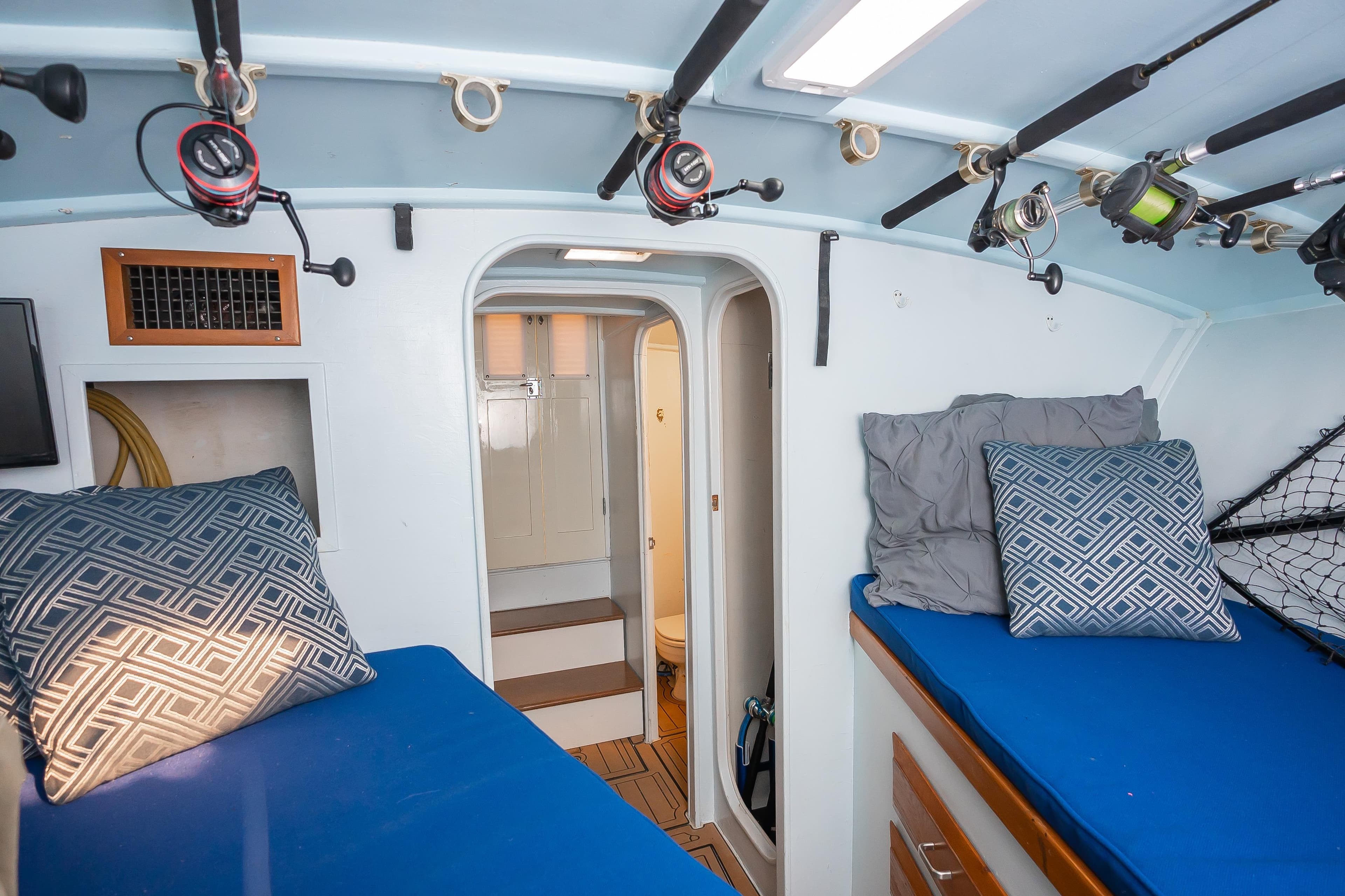 Interior of 1987 Custom Carolina Island Boatworks 34 Express with fishing rods and cozy bedding.