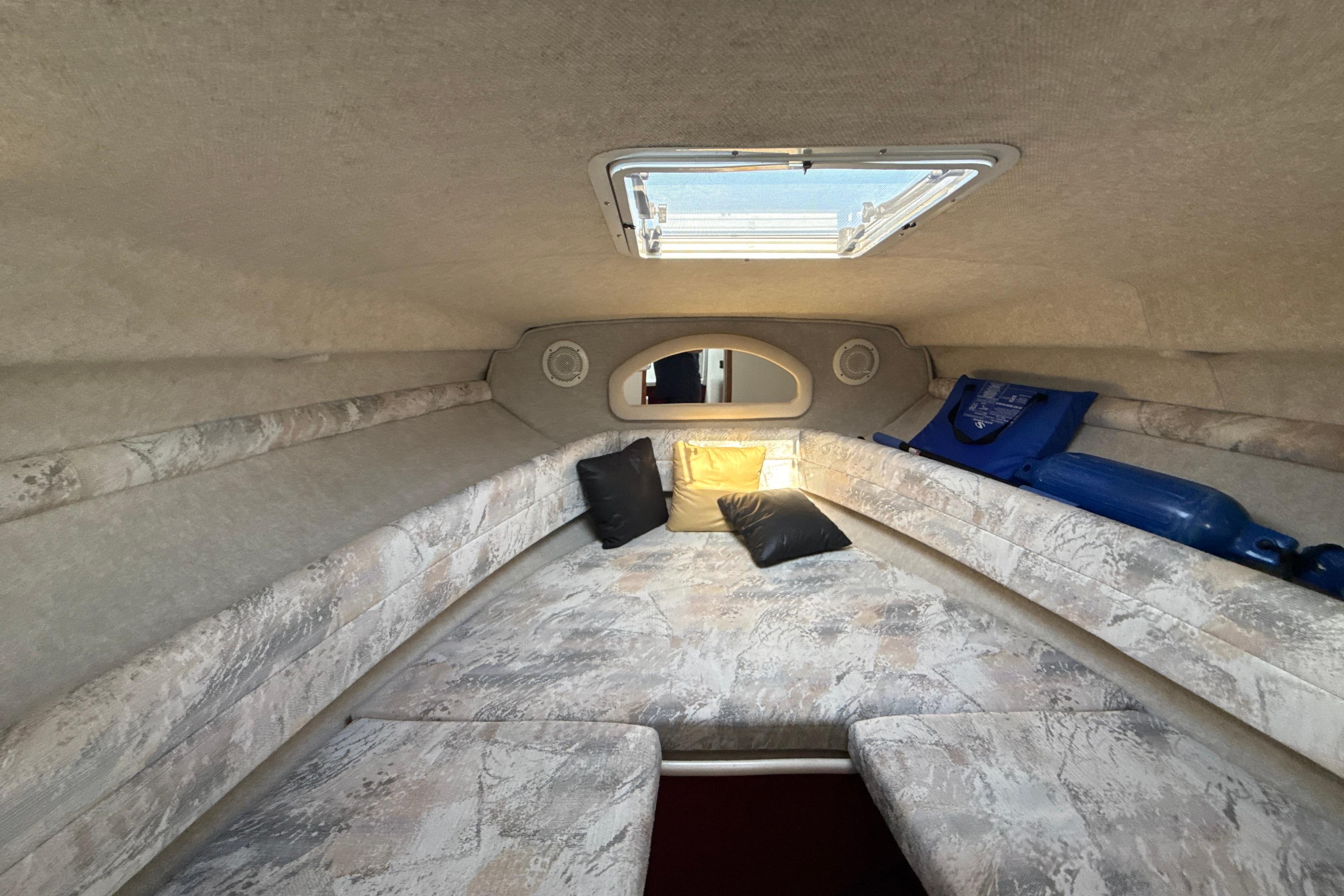 Interior cabin of 1996 Sea Ray 240 Sundancer with cushions and porthole.