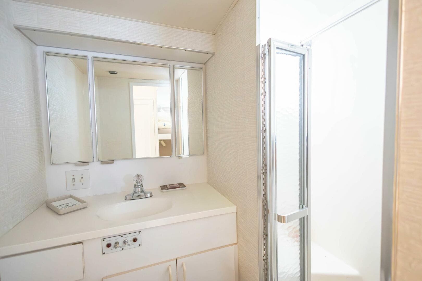 1989 Hatteras Custom Cockpit bathroom with mirrored cabinet and shower.