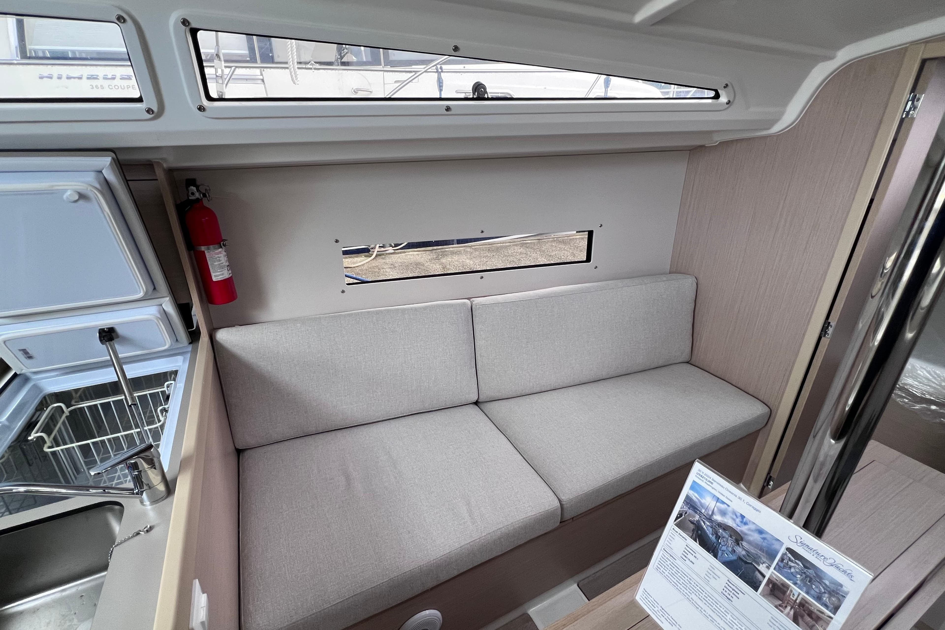 Interior of 2024 Beneteau Oceanis 30.1 yacht with gray sofa and window view.