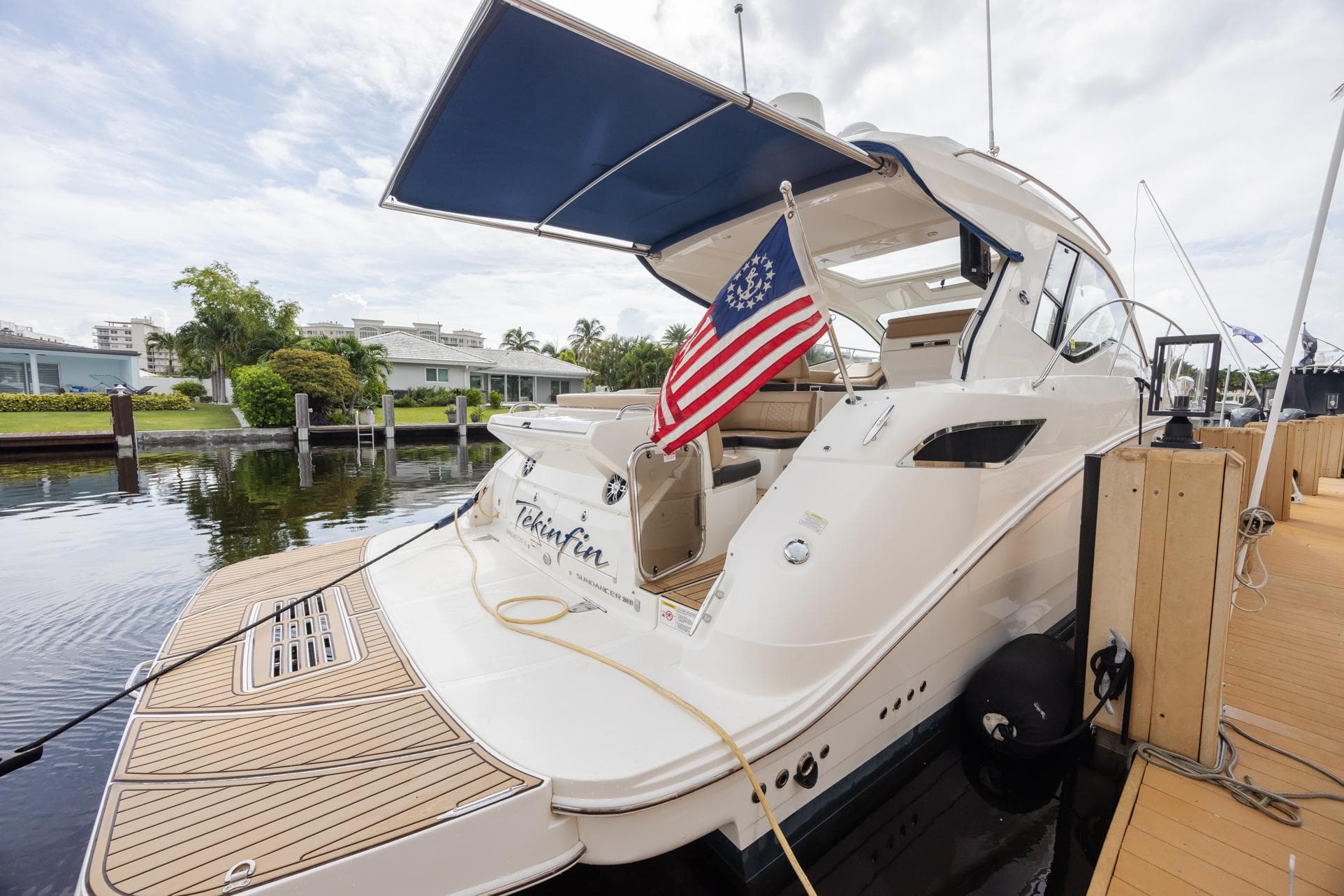 2019 Sea Ray Sundancer 350 Coupe docked with American flag, featuring sleek design and spacious deck.