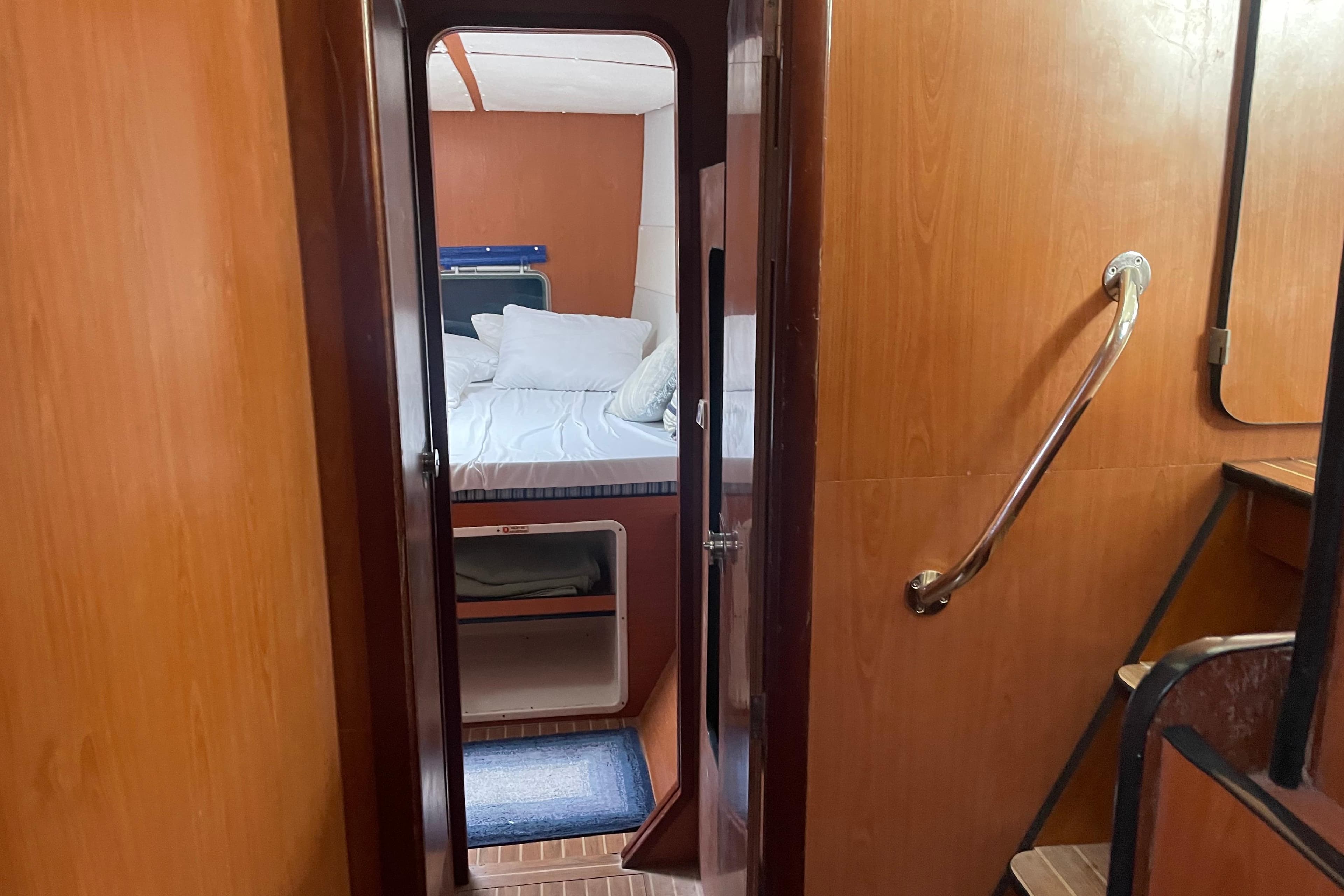 Interior cabin view of 2004 Lagoon 570 yacht, featuring cozy bed and wooden paneling.